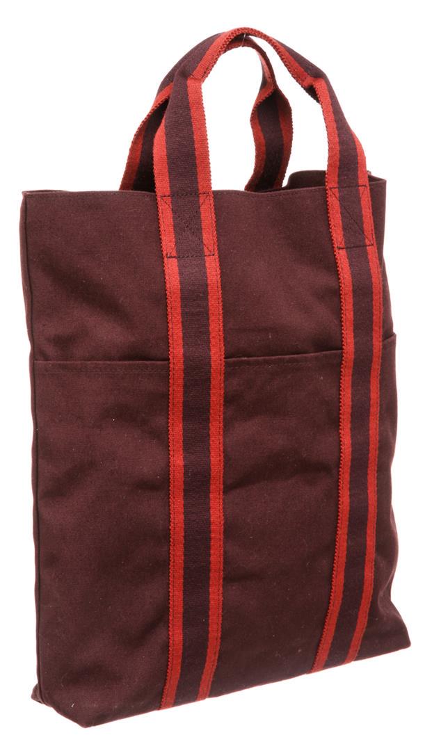 Hermes Burgundy Canvas Vertical Sac Fourre Tote Bag: One Hermes Burgundy Canvas Vertical Sac Fourre Tote Bag. Hermes burgundy canvas vertical Herline tote bag with red stripe handles, interior slip pocket, and three exterior slip pockets. MKX