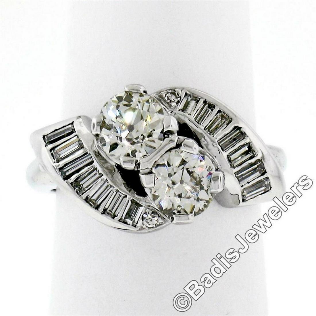 Art Deco Platinum 1.48 ctw Old European and Baguette: A platinum art deco period bypass ring featuring a pair of old European cut diamonds (1.03ctw; I/J - VVS2/VS1) accented by 0.49ctw of baguette and round single cut diamonds (F/G - VVS2 to VS2). The ri