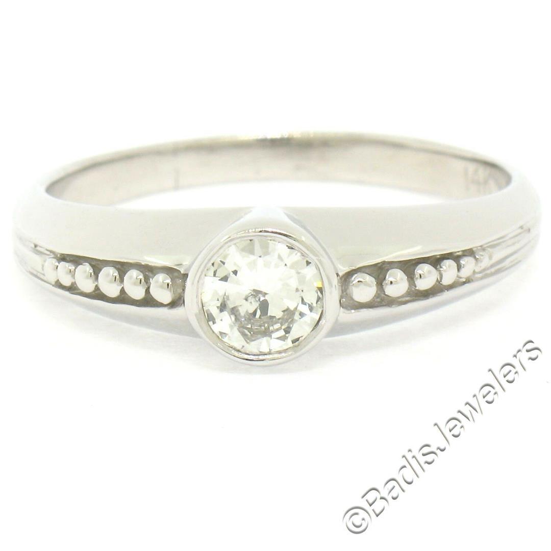 14kt White Gold 0.32 ctw Bezel Set Round Brilliant: A 14kt white gold solitaire ring featuring a round brilliant diamond (F - SI1; 0.32ct) bezel set at its center accented by a simple beading pattern.The ring is size 9.5, weighs a total of 3.64 grams, 