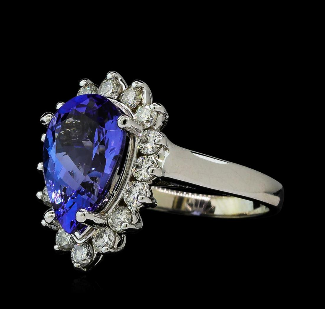 4.81 ctw Tanzanite and Diamond Ring - 14KT White Gold: One electronically tested 14KT white gold ladies cast tanzanite and diamond ring with a bright polish finish. The featured tanzanite is set within a diamond floret supported by a ribbed under gallery 