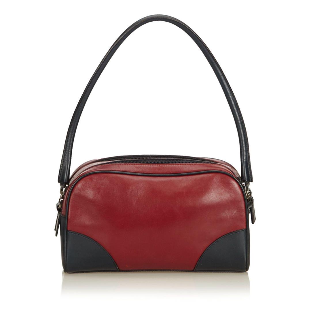 Prada Leather Shoulder Bag: This shoulder bag features a leather body, rolled leather handle, dual compartments with top zip closures, and an interior zip pocket. Measurements: Length: 14 in / 36 cm Width: 23.5 in / 60 cm 7.5 in