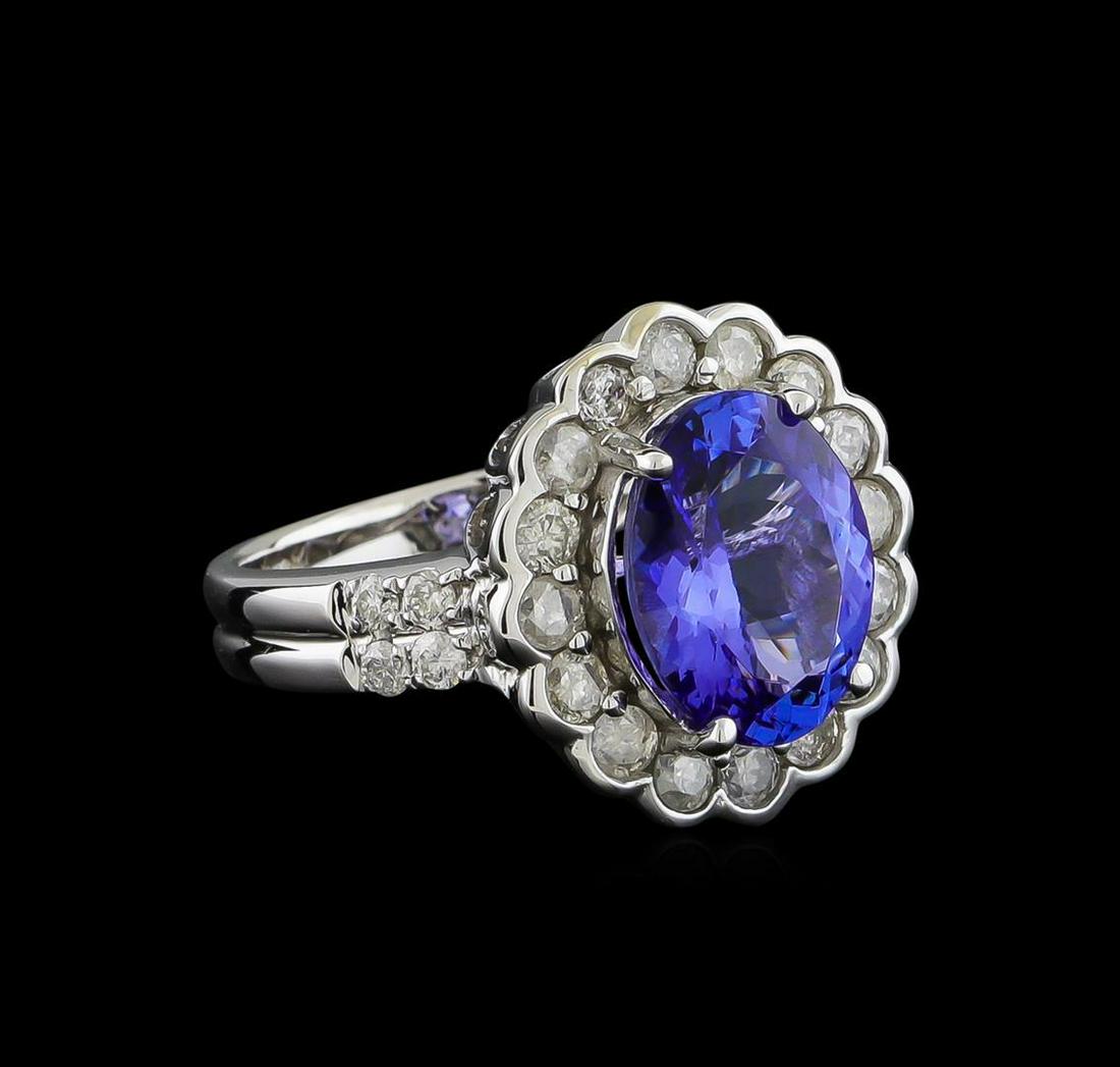 4.04 ctw Tanzanite and Diamond Ring - 14KT White Gold: One electronically tested 14KT white gold ladies cast tanzanite and diamond ring with a bright polish finish. The featured tanzanite is set within a stylized diamond floret bezel supported by diamond 