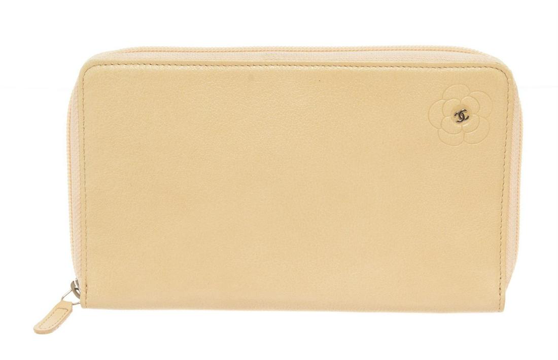 Chanel Ivory Leather Camellia Zip Around Long Wallet: Chanel Camellia Zip Around Long Wallet features ivory leather body with engraved Camellia flower and interlocking CC logo at the center, silver-tone hardware, zipper around the main compartment, one i