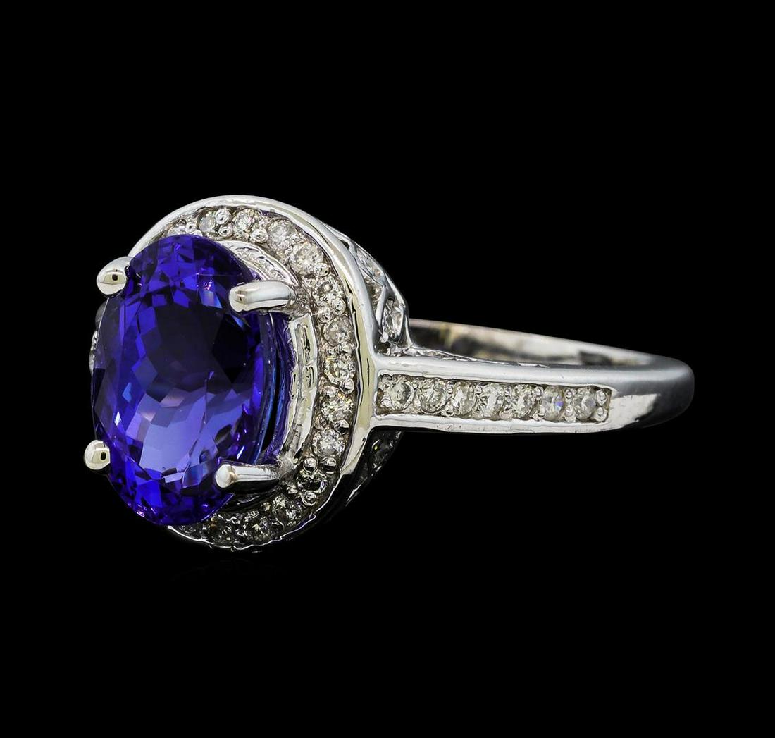 2.94 ctw Tanzanite and Diamond Ring - 14KT White Gold: One electronically tested 14KT white gold lady's cast fashion ring with a cathedral shank with a basket halo with a bright polish finish. The featured lady's ring has a shank measuring 1.54 millimeter