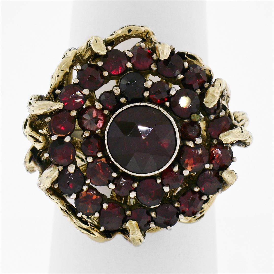 Vintage 14k Yellow Gold and Silver Top Old Cut Garnet Cluster Ring: A vintage 14k yellow gold cluster ring featuring a 7.4mm round garnet set at its center in a sterling silver-topped bezel among 30 additional round cut garnets. The ring is size 7.5, weighs a total of