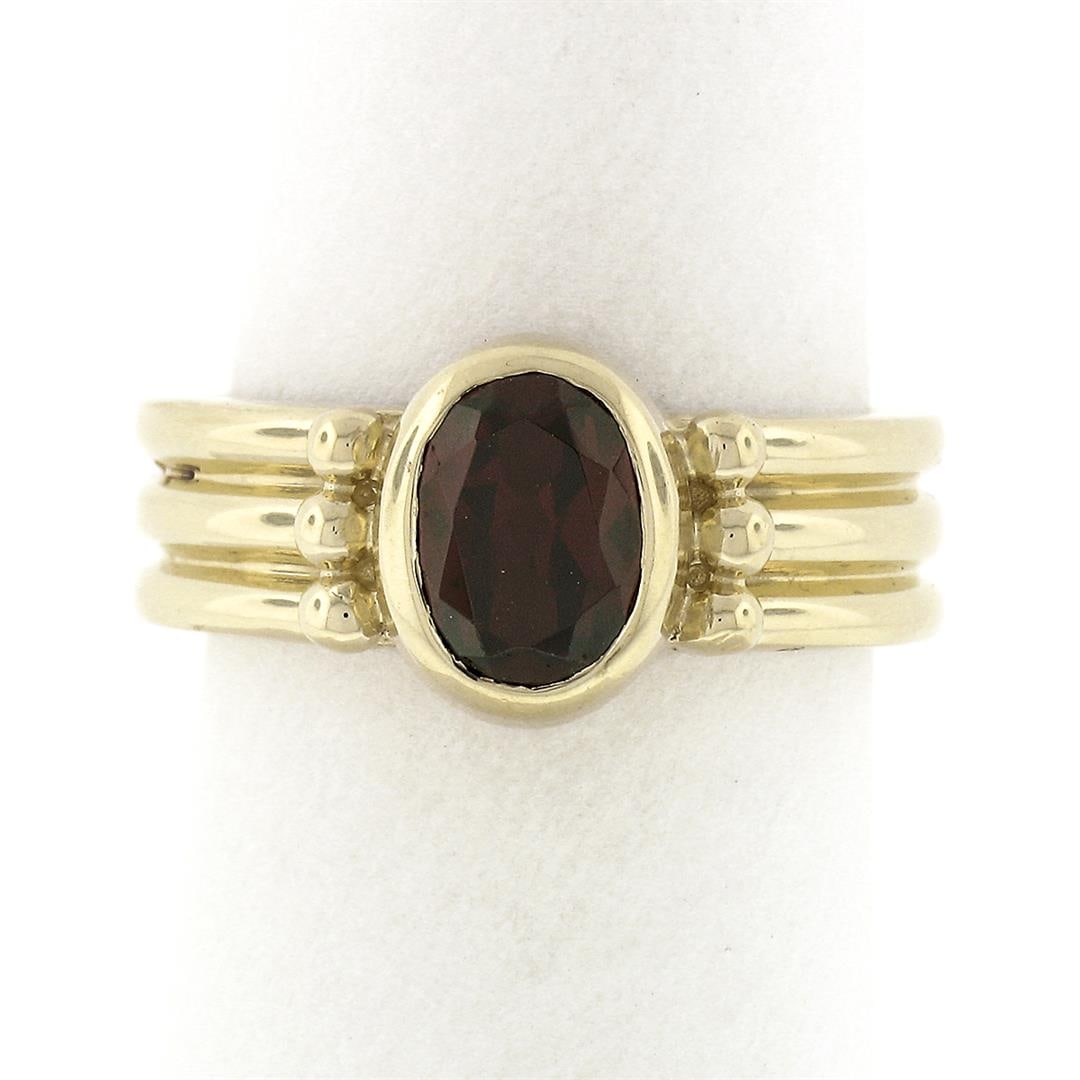 14K Yellow Gold 1.30 ctw Bezel Set Oval Garnet Solitaire Grooved Wide Band Ring: A solid 14k yellow gold solitaire ring, with 1 oval cut natural garnet (7.7x5.2mm - 1.30ct). The ring is size 6.5, weighs a total of 7.40 grams, and measures 9.85mm wide.