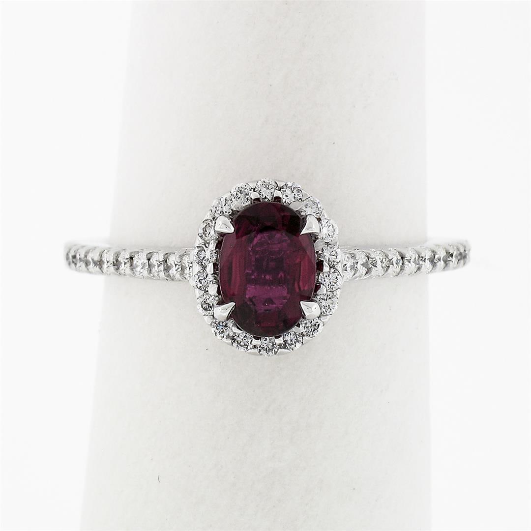 NEW Petite 14k White Gold 1.40 ctw Oval Red Ruby & Diamond Halo Engagement Ring: A new solid 14k white gold solitaire ring, featuring 1 oval brilliant cut natural ruby (0.80ctw), & 40 round brilliant cut natural diamonds (F/G- VS1/VS2; 0.60ctw). The ring is size 6.0, weighs a tota