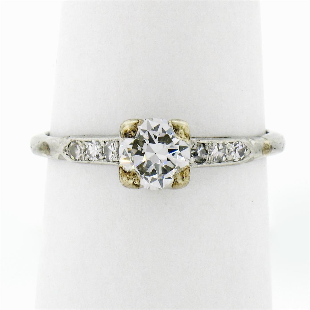 Antique Art Deco Platinum .65 ctw Transitional Diamond Engagement Ring w/ Accent: An antique solid platinum solitaire ring, featuring 1 transitional cut natural diamond (E - VS1 ; 0.56ct), and 6 round single cut natural diamonds (F - VS2 ; 0.09ctw ). The ring is size 7.0, weighs a