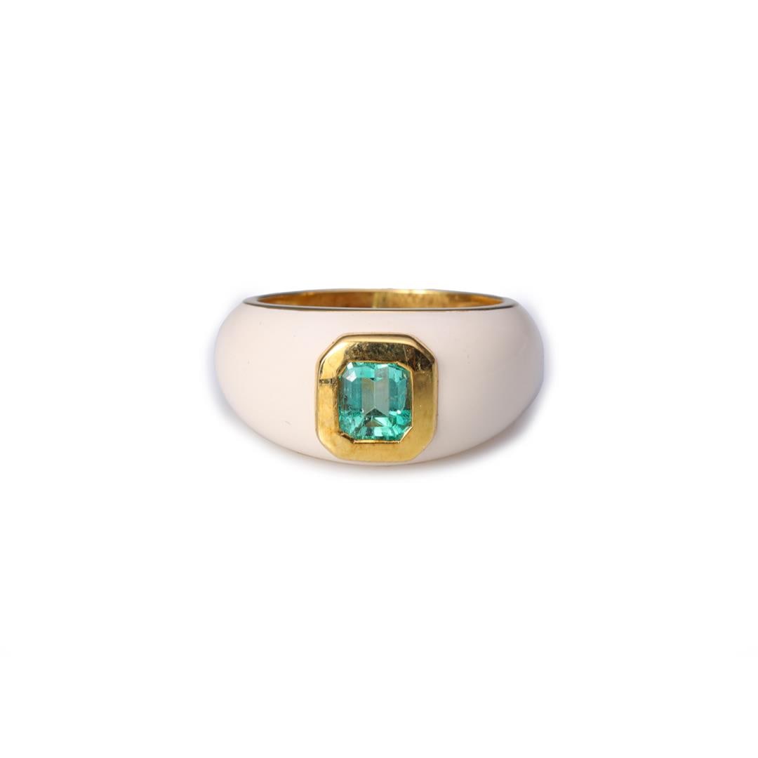 18K Yellow Gold Enamel & Emerald Ring: A center emerald bezel set in an 18k yellow gold ring with white enameling to shoulders and shank, marked 18k to interior band; overall good condition; gross weight 11.2 g, size 7