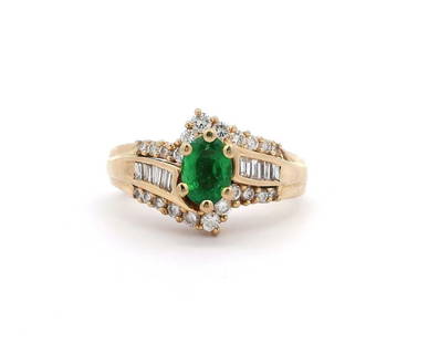 14kt YG Emerald and Diamond Bypass Ring: This 14KT yellow gold bypass ring showcases an oval modified brilliant-cut natural emerald weighing 0.70ct, displaying a medium green color with slight inclusions. Flanking the emerald are twenty-two