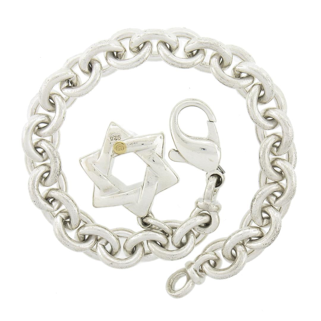 6.25" Movado .925 Silver Round Link Bracelet w/ Polished Star of David Charm: A solid silver star of David dangle charm round link bracelet by MOVADO. It weighs a total of 29.61 grams, measures 7.8mm wide, and measures 6.25 inches in length, the charm measures 25.1x17mm.