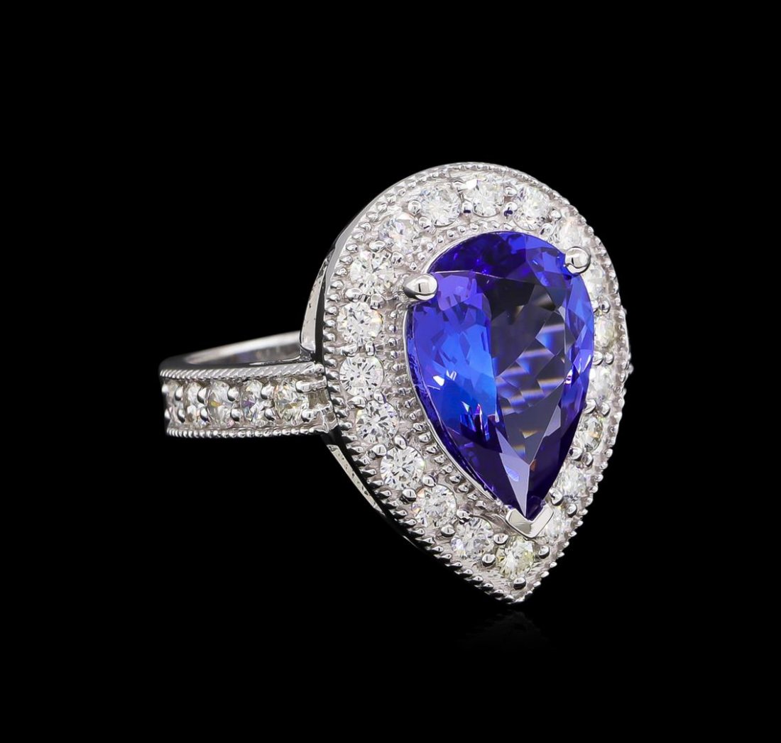 3.30 ctw Tanzanite and Diamond Ring - 14KT White Gold: One electronically tested 14KT white gold lady's cast fashion ring with a cathedral shank with a halo with a bright polish with milgrain detailing finish. The featured lady's ring has a shank measurin