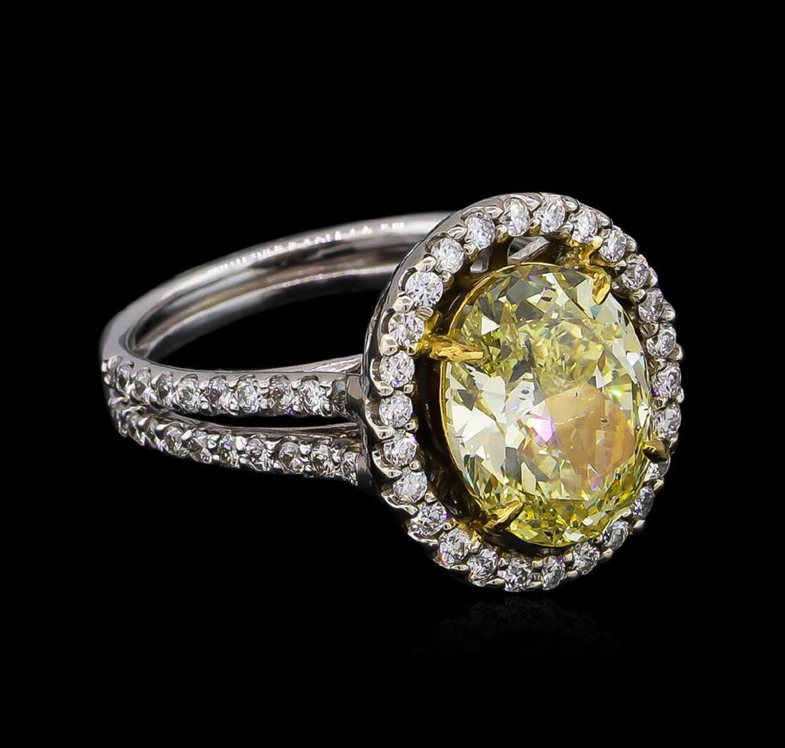 14KT White Gold 4.74 ctw Fancy Yellow Diamond Ring: One electronically tested 14KT white gold ladies cast diamond ring with a bright polish finish. The featured diamond is set within an inner yellow gold basket and an outer diamond bezel supported by d