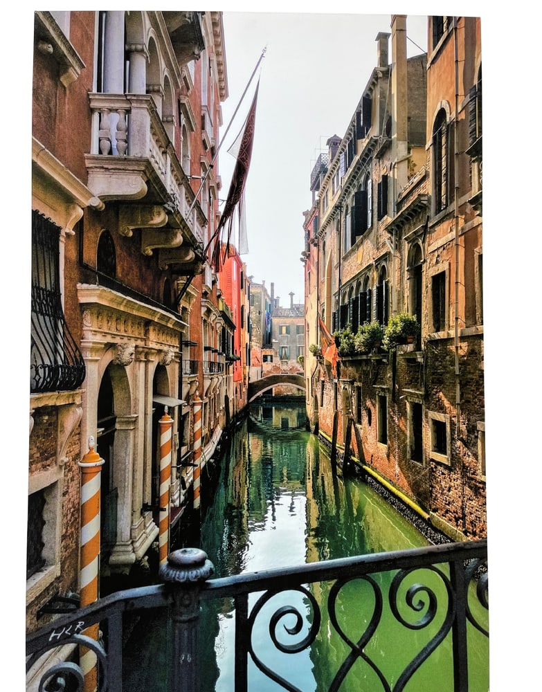 Venetian Canal Photo on Canvas: This lovely photo of a Venetian Canal was placed on canvas, making it a wonderful piece to warm any room. Professionally mounted with wrapped edges make this piece easy to hang with no need of