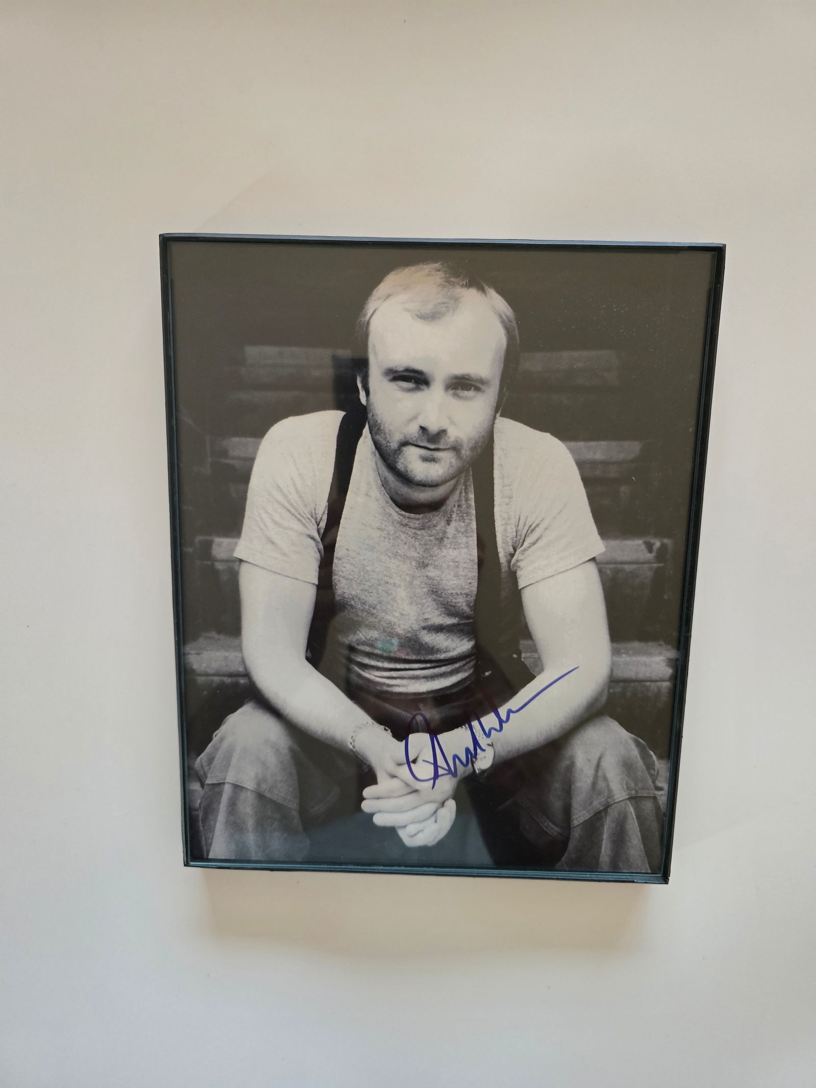 Autographed Phil Collins Photograph Framed W/COA: This striking photograph features Phil Collins, the legendary singer, songwriter, and drummer, personally hand-signed by the iconic musician. The autograph is bold, clear, and prominently displayed, m