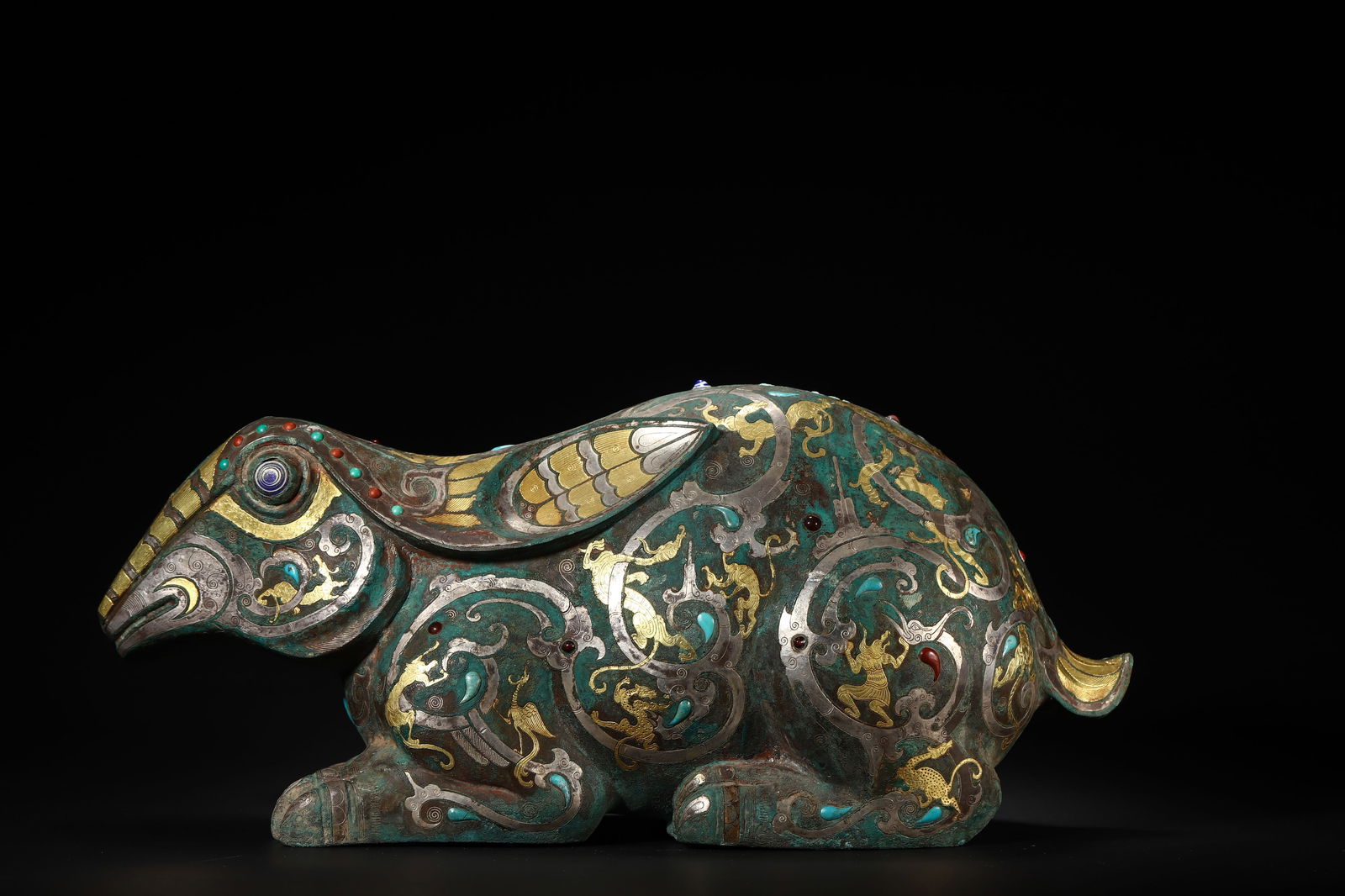 Han Dynasty Bronze Gold-and-Silver-Inlaid Gemstone Mythical Beast-Form Vessel: Length 34.0cm (13.39in), Width 14.0cm (5.51in), Height 15.0cm (5.91in), Weight 5225.0g (11.52lb)Shaped as a crouching auspicious beast, bronze body with gold and silver inlays, inlaid with turquoise,