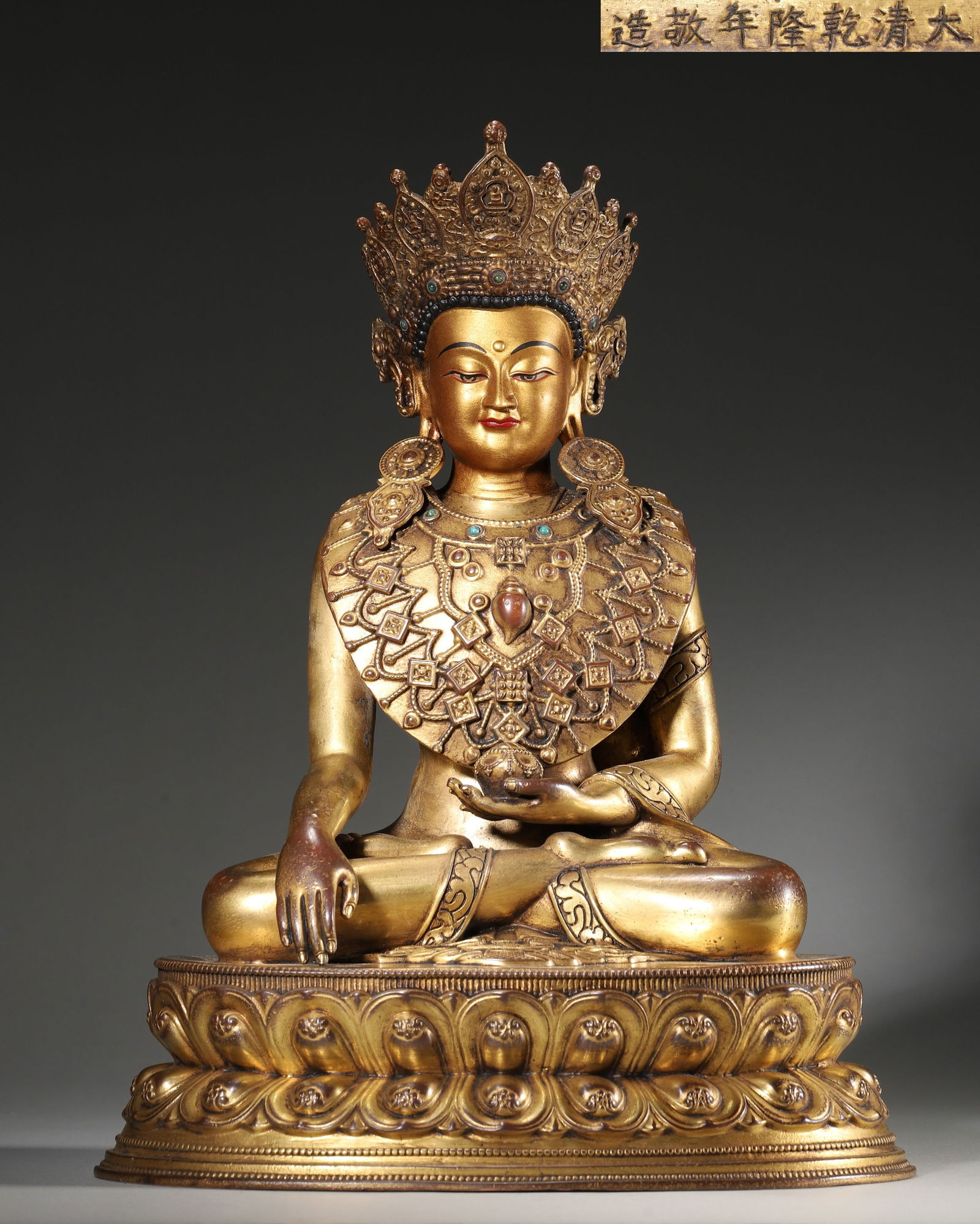 An Imperial Gilt-Bronze Seated Figure of Amitayus, Qing Dynasty, Qianlong Period: Width 23.0cm (9.06in), Height 33.0cm (12.99in), Weight 4531.0g (9.99lb)With the "Da Qing Qianlong Nian Jing Zao" mark, fully gilt-bronze, crown inlaid with gemstones and body adorned with beaded jewel