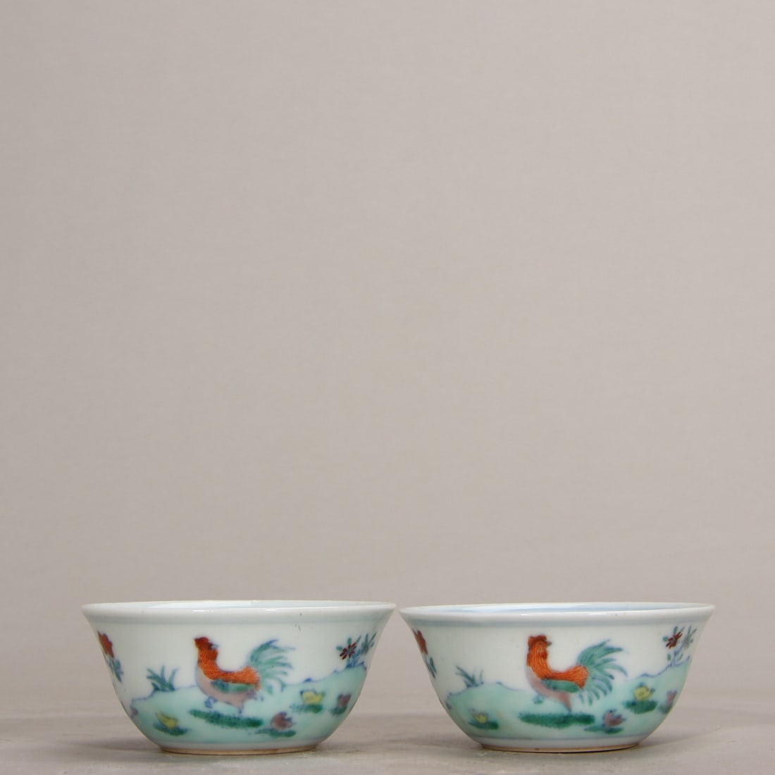 Qing Dynasty Kangxi Period, A Pair of Doucai Chicken Cups: Height: 2.8cm CAL6.4cmA pair of Doucai chicken cups from the Kangxi period of the Qing Dynasty, imitating Chenghua style. With fine thin bodies, delicate colors, and vivid chicken motifs, they