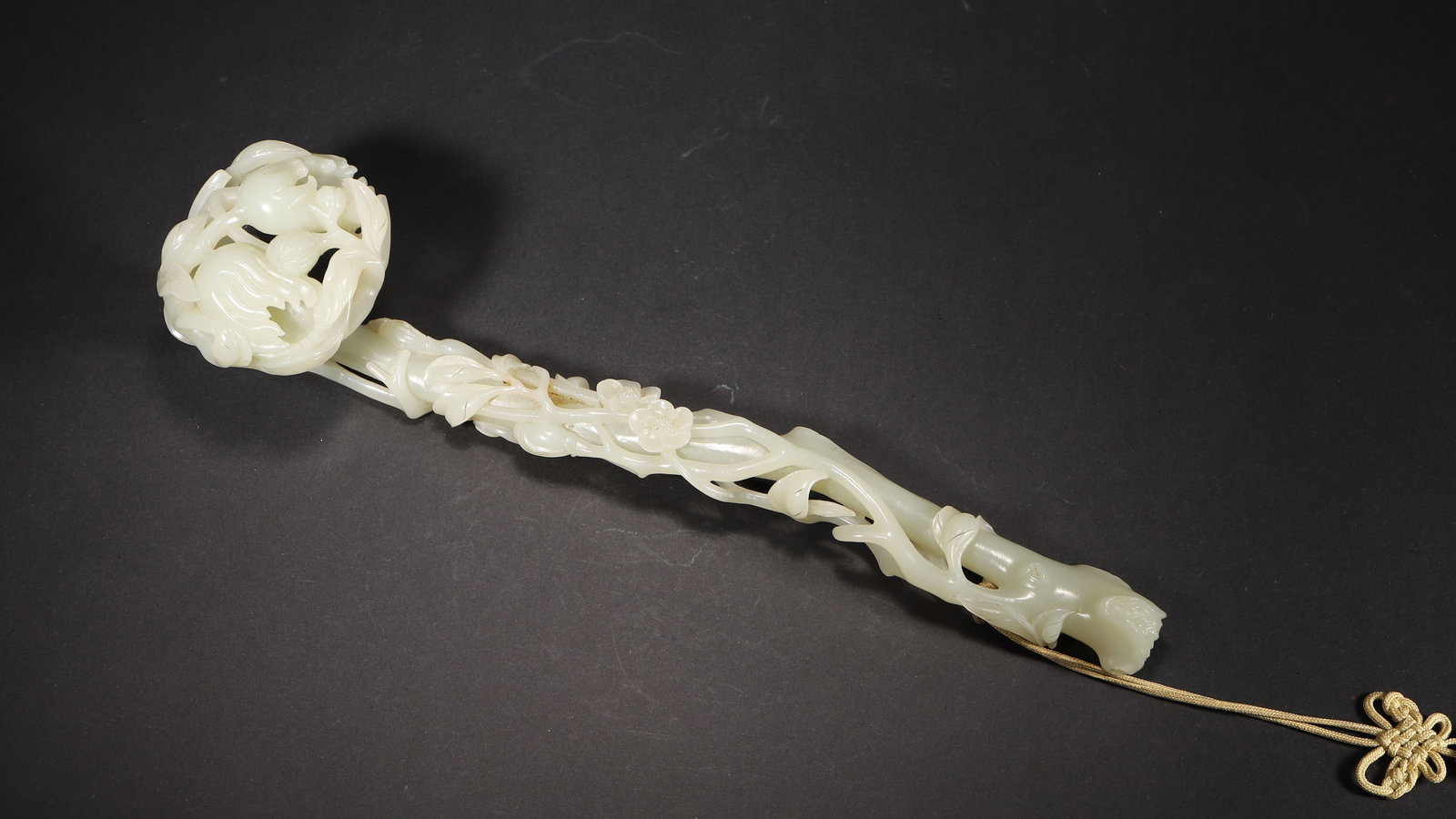 QING DYNASTY, WHITE HETIAN JADE OPENWORK RUYI WITH BUDDHA'S HAND AND FLORAL MOTIFS: 10.25" x 2.38" (26.0cm x 6.0cm) | 0.44lbA Qing Dynasty imperial-style white Hetian jade ruyi, intricately carved with openwork Buddha's hand, plum branches and flowers. Exquisite craftsmanship, warm a