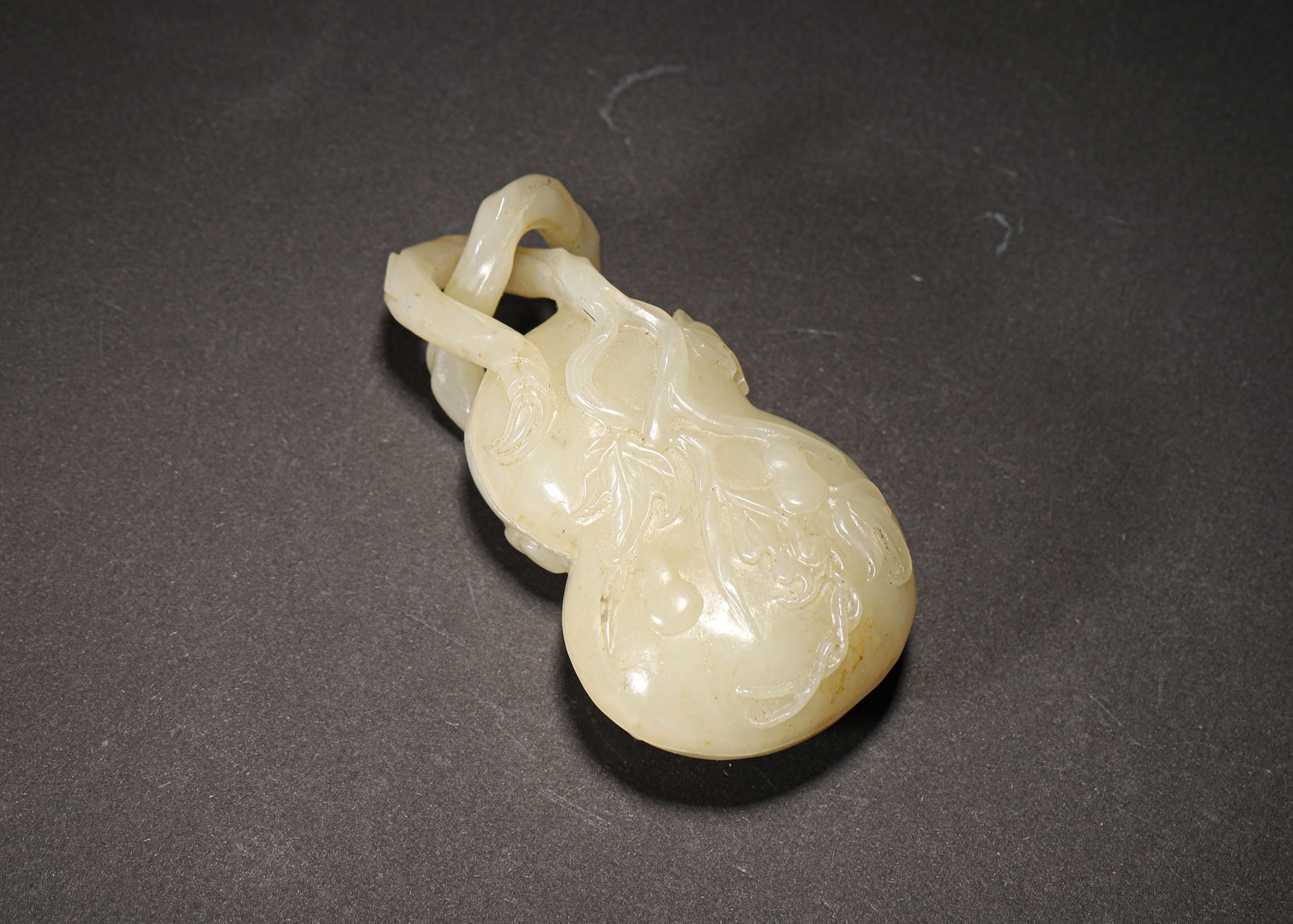 MID-QING DYNASTY, WHITE HETIAN JADE GOURD-FORM BOX WITH LINKED RINGS: 3.12" x 1.75" (8.0cm x 4.5cm) | 0.19lbCarved from a single piece of warm white Hetian jade, this mid-Qing Dynasty gourd-form box features integrated movable rings and delicate vine relief carving, sym
