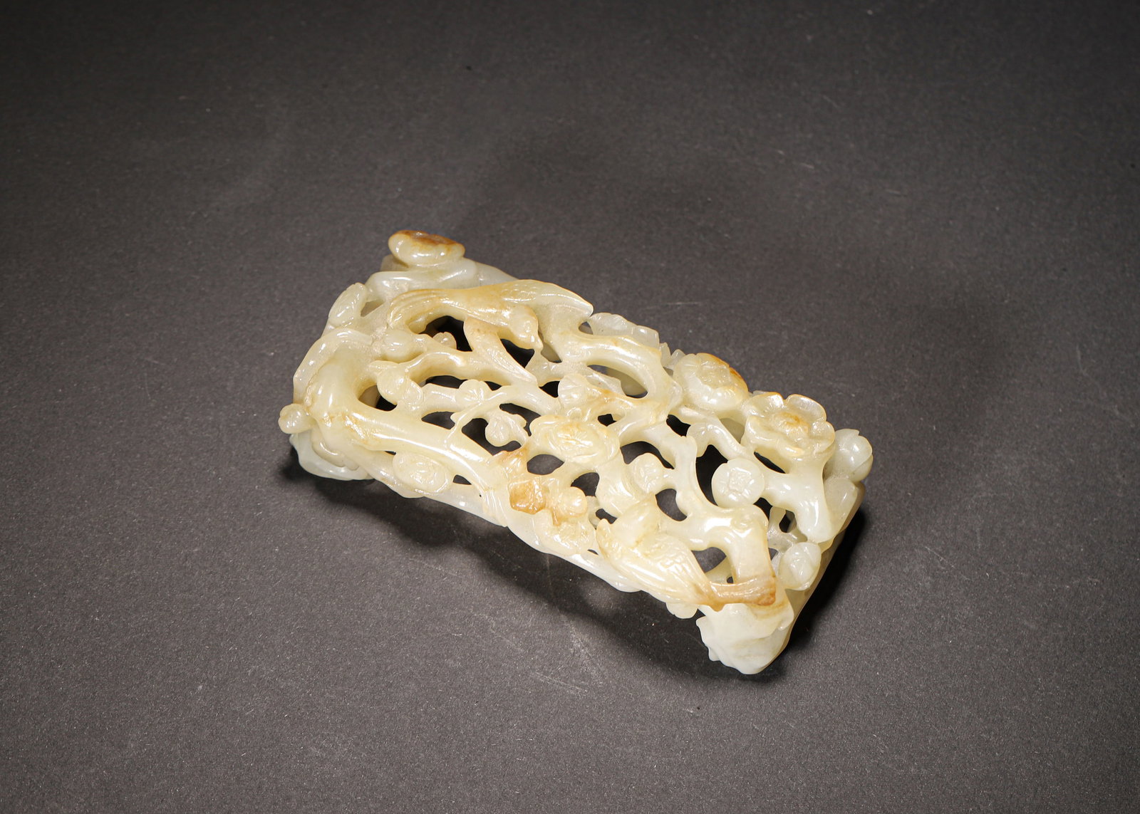 MID-QING DYNASTY, WHITE HETIAN JADE INK REST WITH RETAINED SKIN AND OPENWORK PLUM BLOSSOM: 3.75" x 1.75" x 1.12" (9.5cm x 4.5cm x 2.8cm) | 0.18lbFinely carved from white Hetian jade, this mid-Qing Dynasty ink rest features multi-layered openwork plum blossom branches with naturally retained