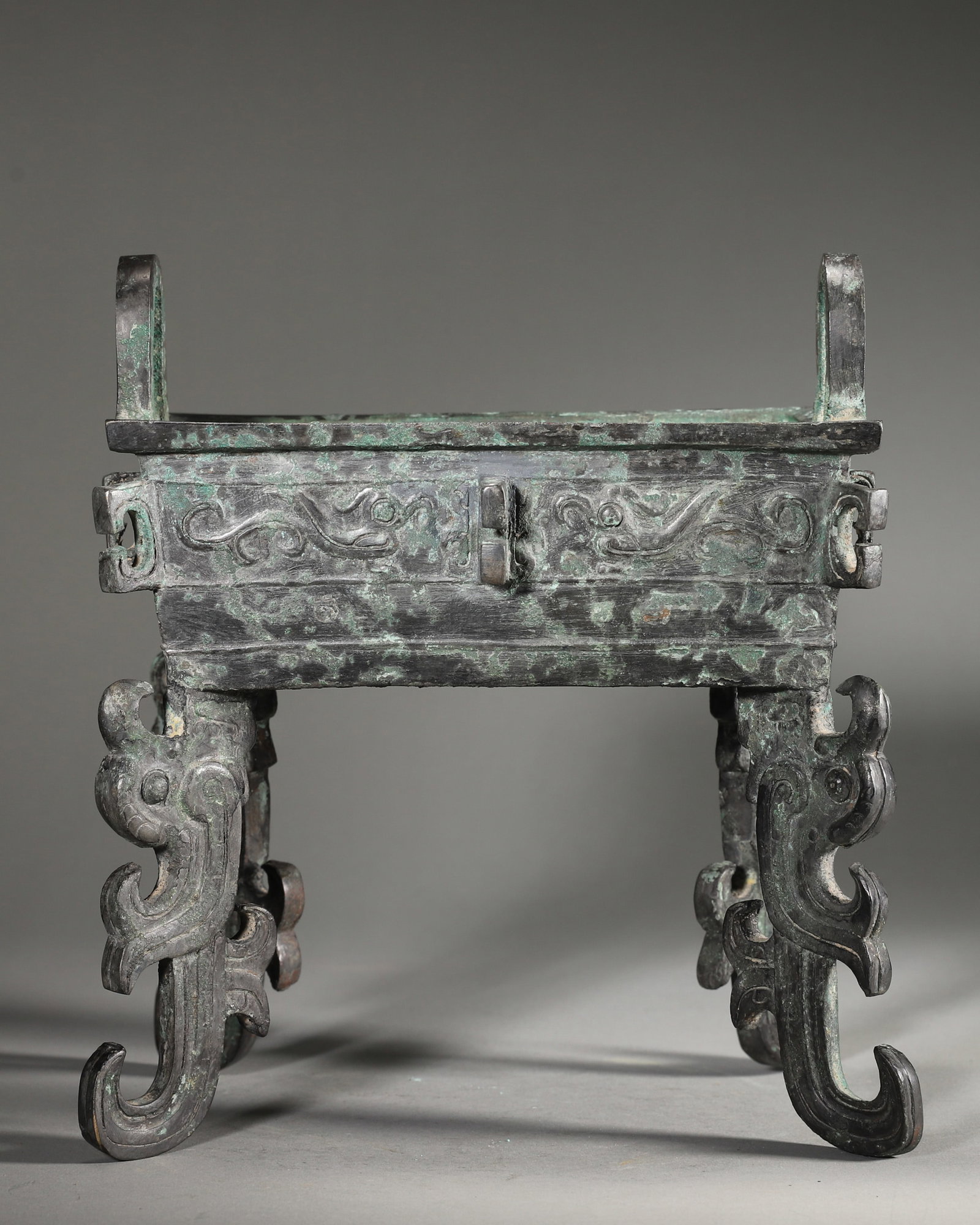 AN IMPORTANT ARCHAIC BRONZE SQUARE DING WITH BIRD-FOOT SUPPORTS, EARLY WESTERN ZHOU DYNASTY: L:18cm (7.09in) W:12cm (4.72in) H:21cm (8.27in) WT:2404g (5.30lb)A fine archaic bronze square ding, Early Western Zhou dynasty, with phoenix patterns and bird-shaped supports, of excellent craftsmansh