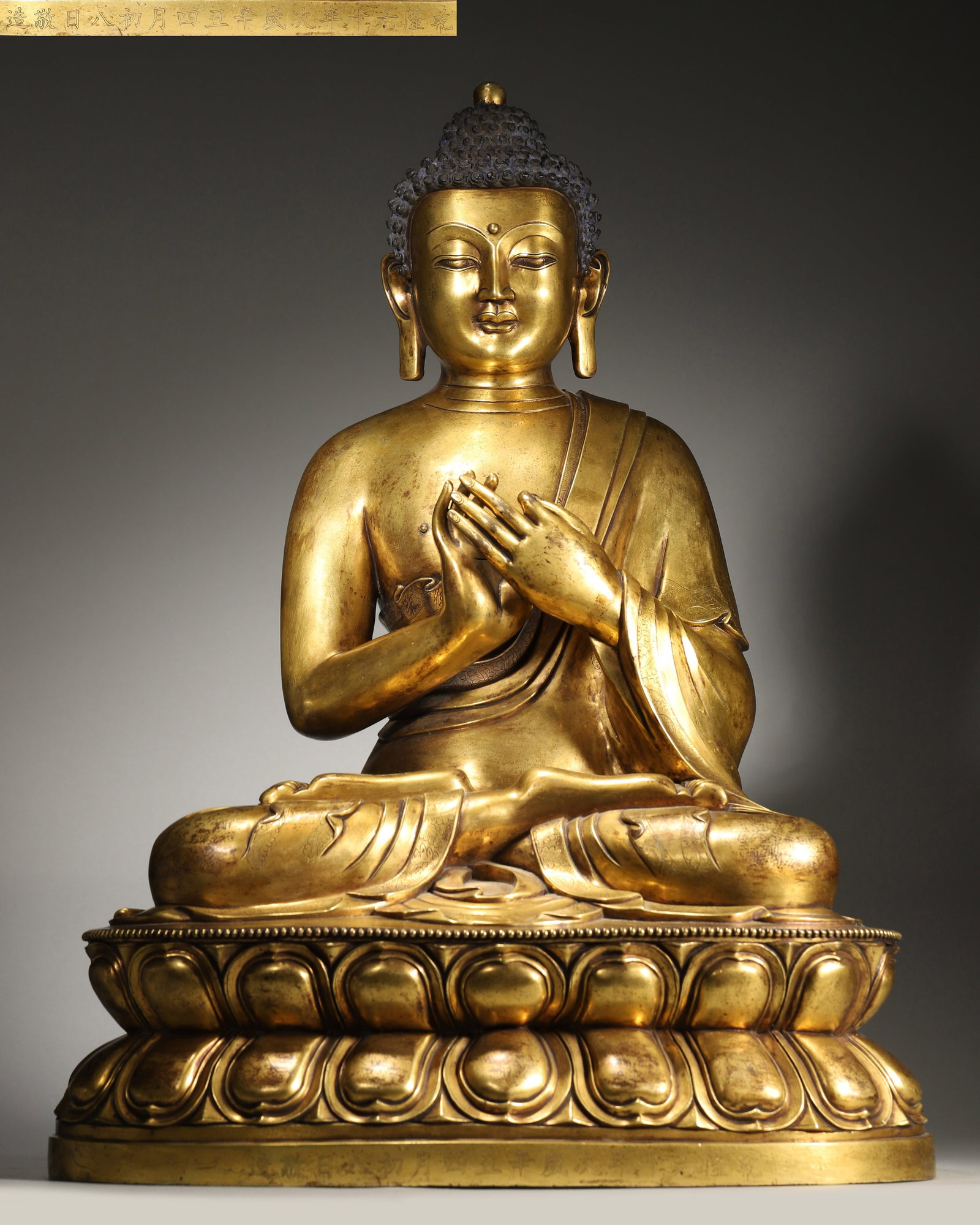 A QIANLONG PERIOD (1736 - 1795) IMPERIAL COURT-MADE GILT-BRONZE FIGURE OF SHAKYAMUNI,QING: 17.32" x 11.02" x 21.65" (44cm x 28cm x 55cm) | 59.42 lbs (26950g)A fine imperial gilt-bronze figure of Shakyamuni Buddha, Qianlong period, Qing dynasty. Well-cast with serene expression, crisp robes,