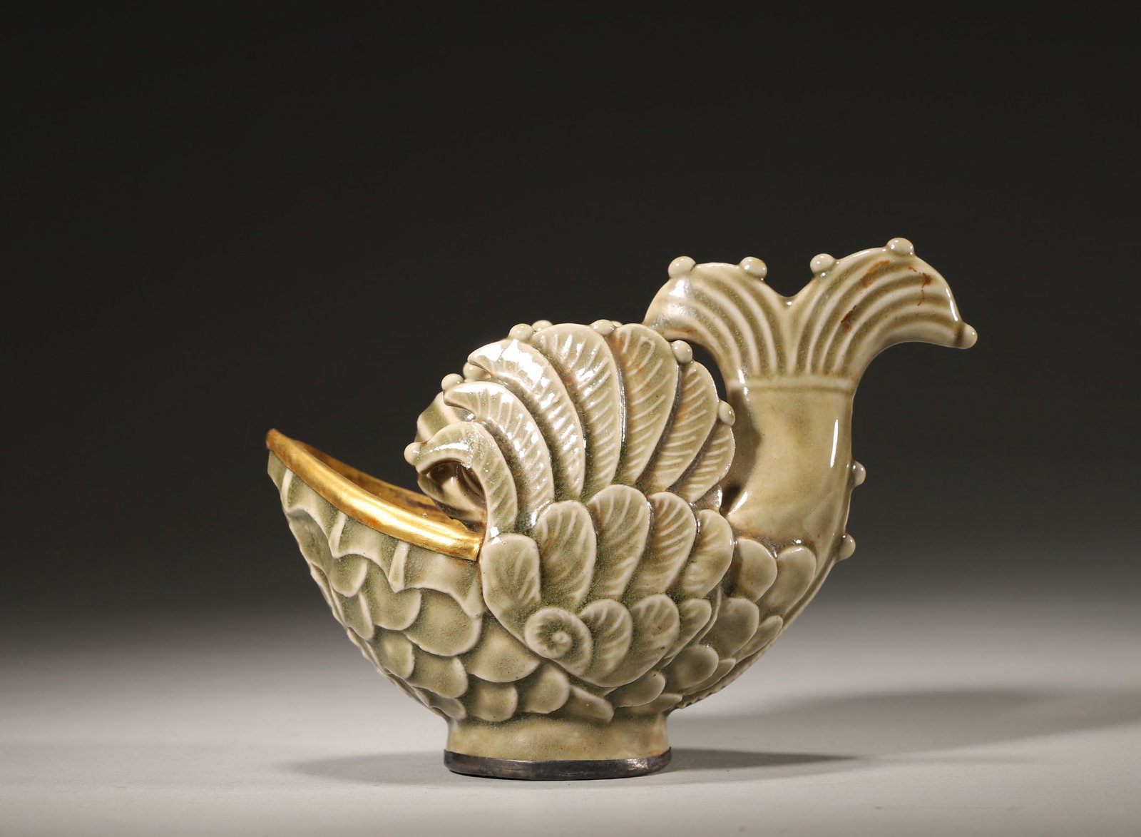 A FIVE DYNASTIES TO EARLY NORTHERN SONG YAOZHOU CELADON 'FISH-DRAGON' CUP: 5.51" x 2.76" x 3.94" inches (14.0 cm x 7.0 cm x 10.0 cm)Ingeniously modelled as a fish-dragon, it features intricate appliqué decoration and a mellow celadon glaze. A pivotal work showcasing Yaozhou
