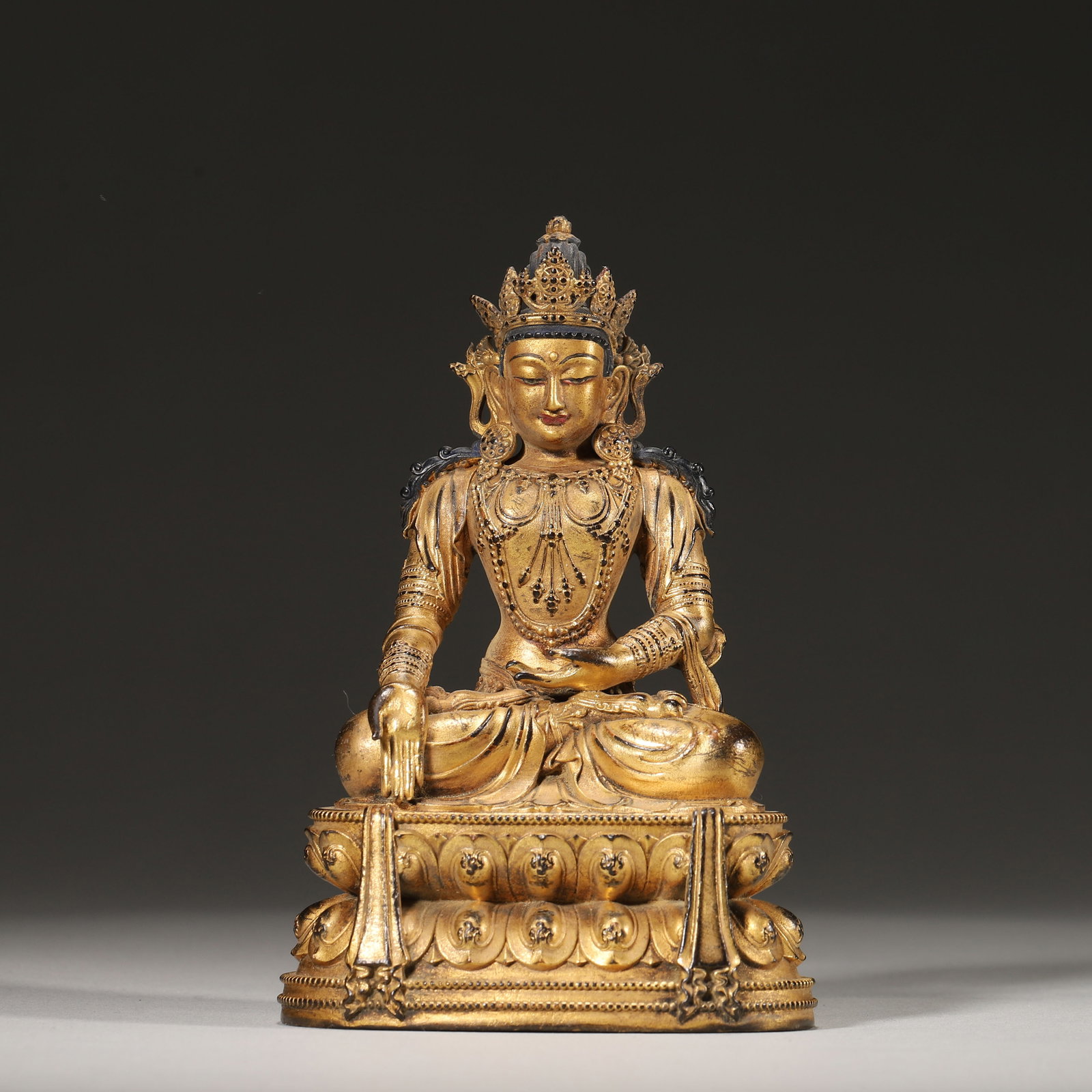 GILT-BRONZE FIGURE OF AKSHOBHYA, MING DYNASTY (16TH-17TH CENTURY): 2.76" x 2.17" x 4.33" (7cm x 5.5cm x 11cm) | 0.56 lbs (253g)A fine gilt-bronze figure of Akshobhya, Ming dynasty (16th-17th century), seated in vajrasana on a double-lotus base, with hands in bhumispa