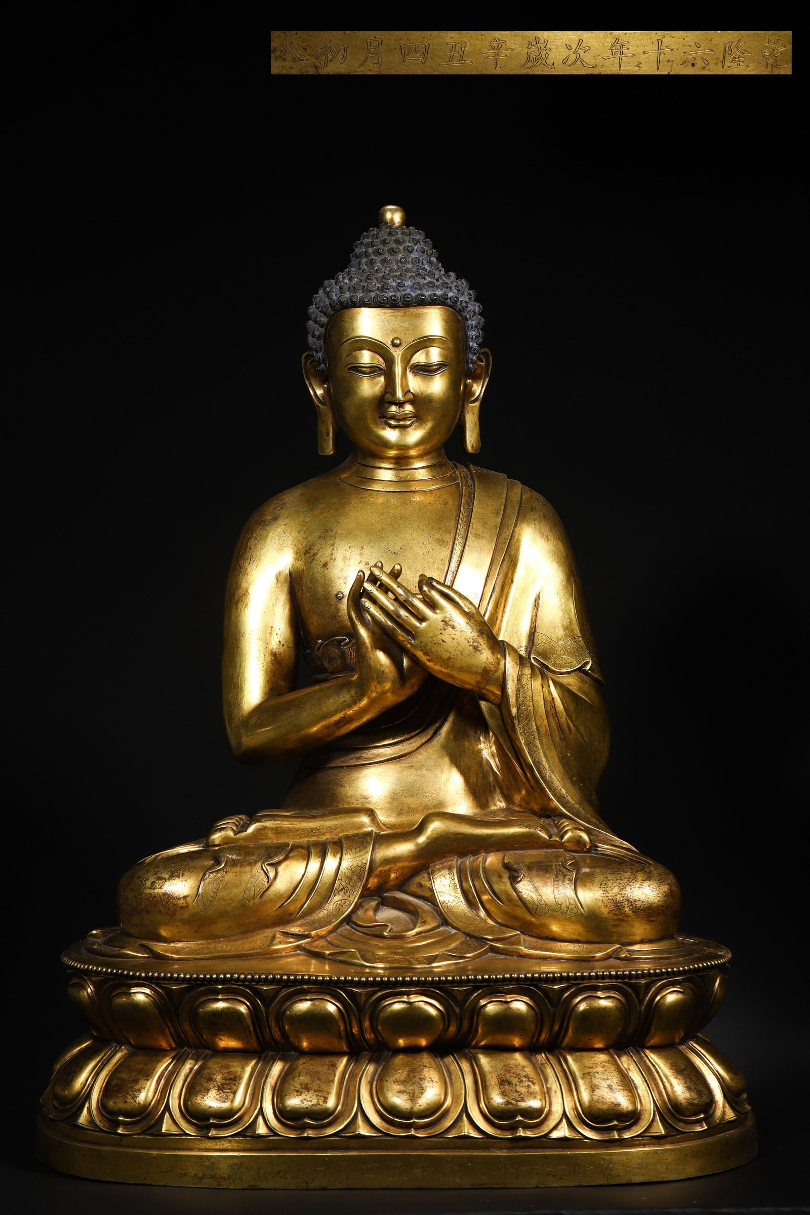 QING DYNASTY QIANLONG PERIOD, IMPERIAL WORKSHOP-MADE GILT-BRONZE SAKYAMUNI SEATED STATUE: Width 40.0cm (15.75in), Height 57.0cm (22.44in)Overall Gilt, Lacquered in Purple-Crimson & Indigo, Seated in Cross-Legged Pose, Lotus Base Carved with Reign Date. An Imperial Buddha Statue Made by the