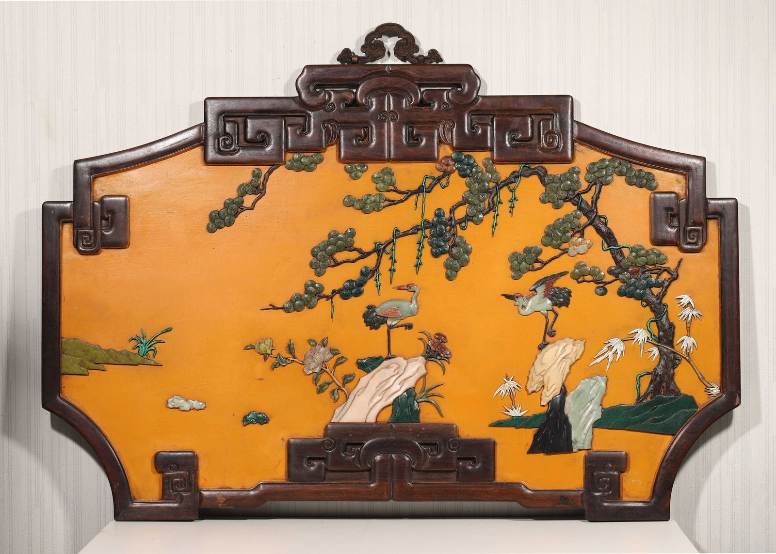 A ZITAN WOOD AND YELLOW LACQUER WALL SCREEN INLAID WITH GEMSTONES, PINE AND CRANE MOTIF, QIANLONG: 43.75" x 28.75" (111.0cm x 73.0cm)This wall screen features a zitan wood frame, yellow lacquer background, and gemstone-inlaid "pine and crane" motif. Exquisitely crafted, it was an imperial display p