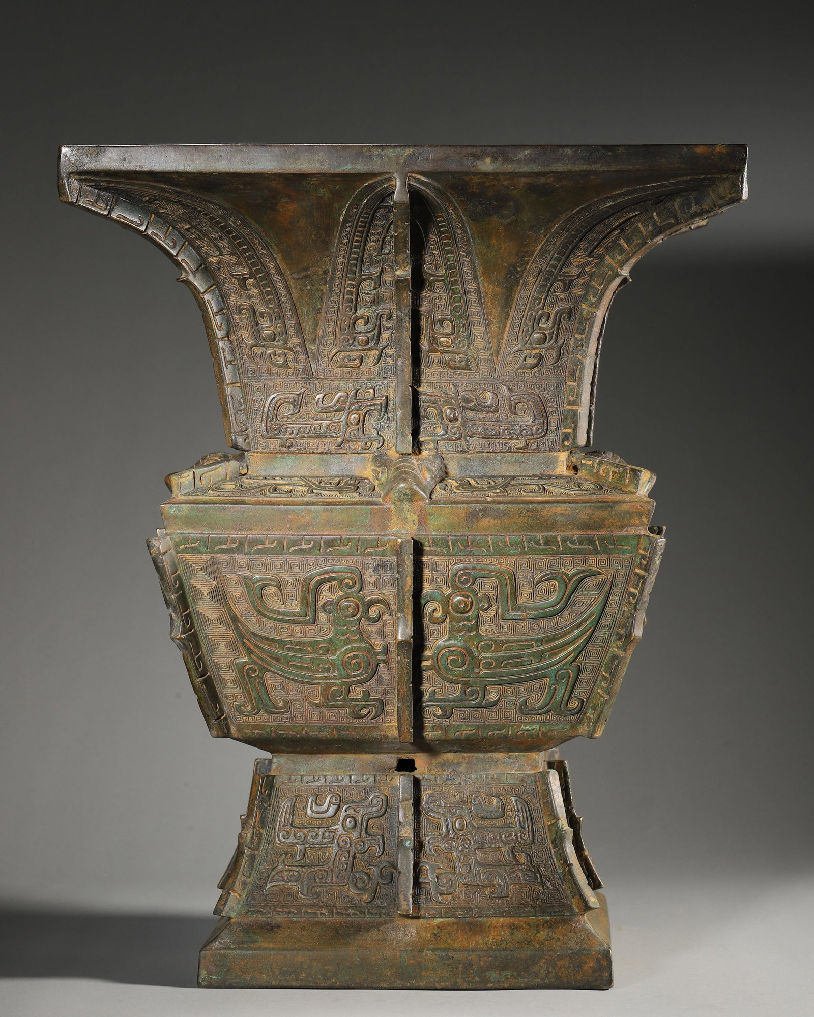 AN IMPORTANT ARCHAIC BRONZE SQUARE RITUAL VESSEL (ZUN), LATE SHANG TO EARLY WESTERN ZHOU DYNASTY: L:31cm (12.20inches) W:31cm H:39cm WT:13.2kgA fine archaic bronze square ritual vessel (zun), Late Shang to Early Western Zhou dynasty, with prominent phoenix and taotie masks, flanges, and an