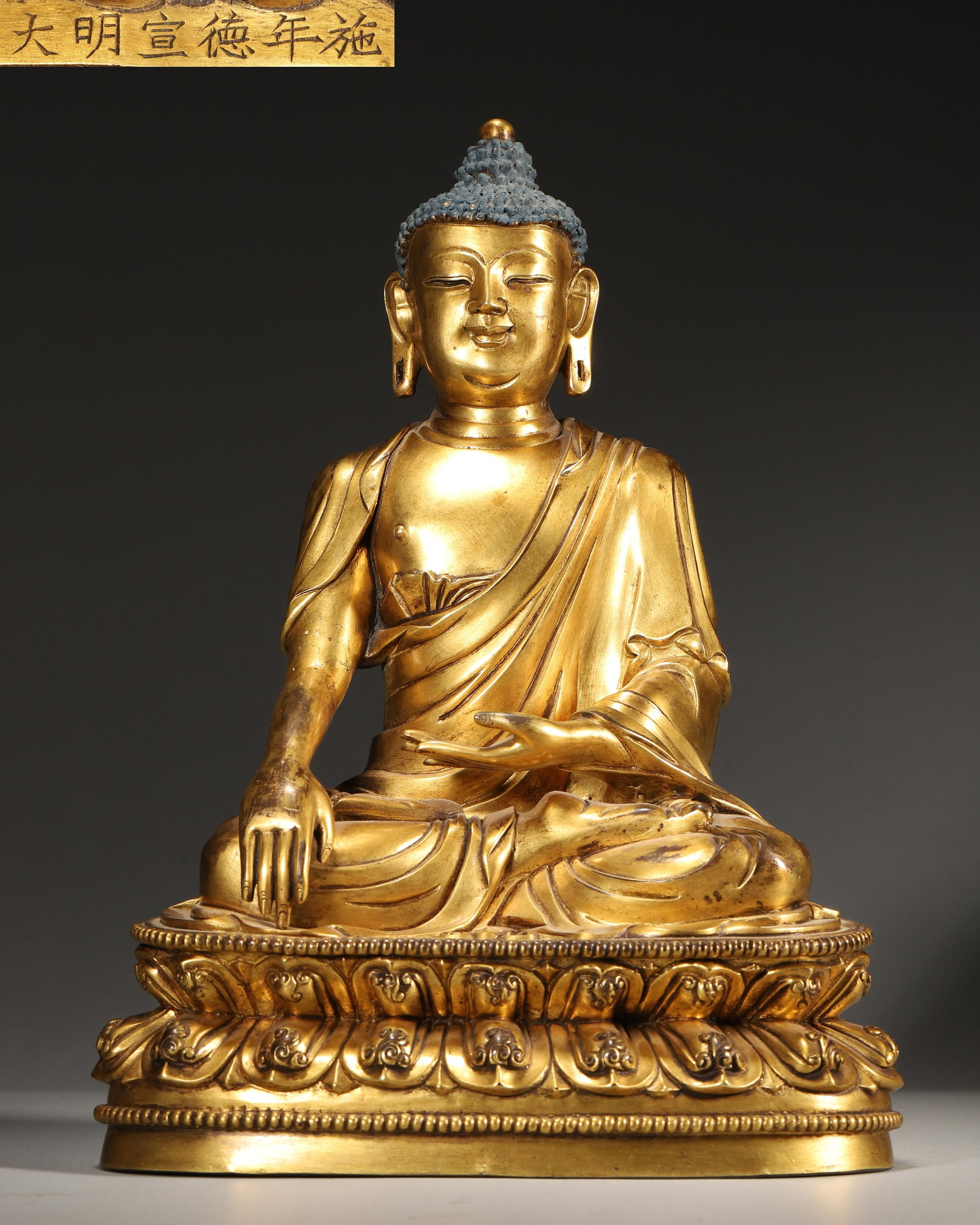 A XUANDE PERIOD (1426-1435) IMPERIAL COURT-MADE GILT-BRONZE SAKYAMUNI BUDDHA,MING DYNASTY,CHINA: 7.09" x 4.33" x 9.45" (18cm x 11cm x 24cm) | 8.86 lbs (4017g)A fine imperial gilt-bronze seated Shakyamuni Buddha, Xuande mark and period, with right hand in bhumisparsha mudra, seated on a double