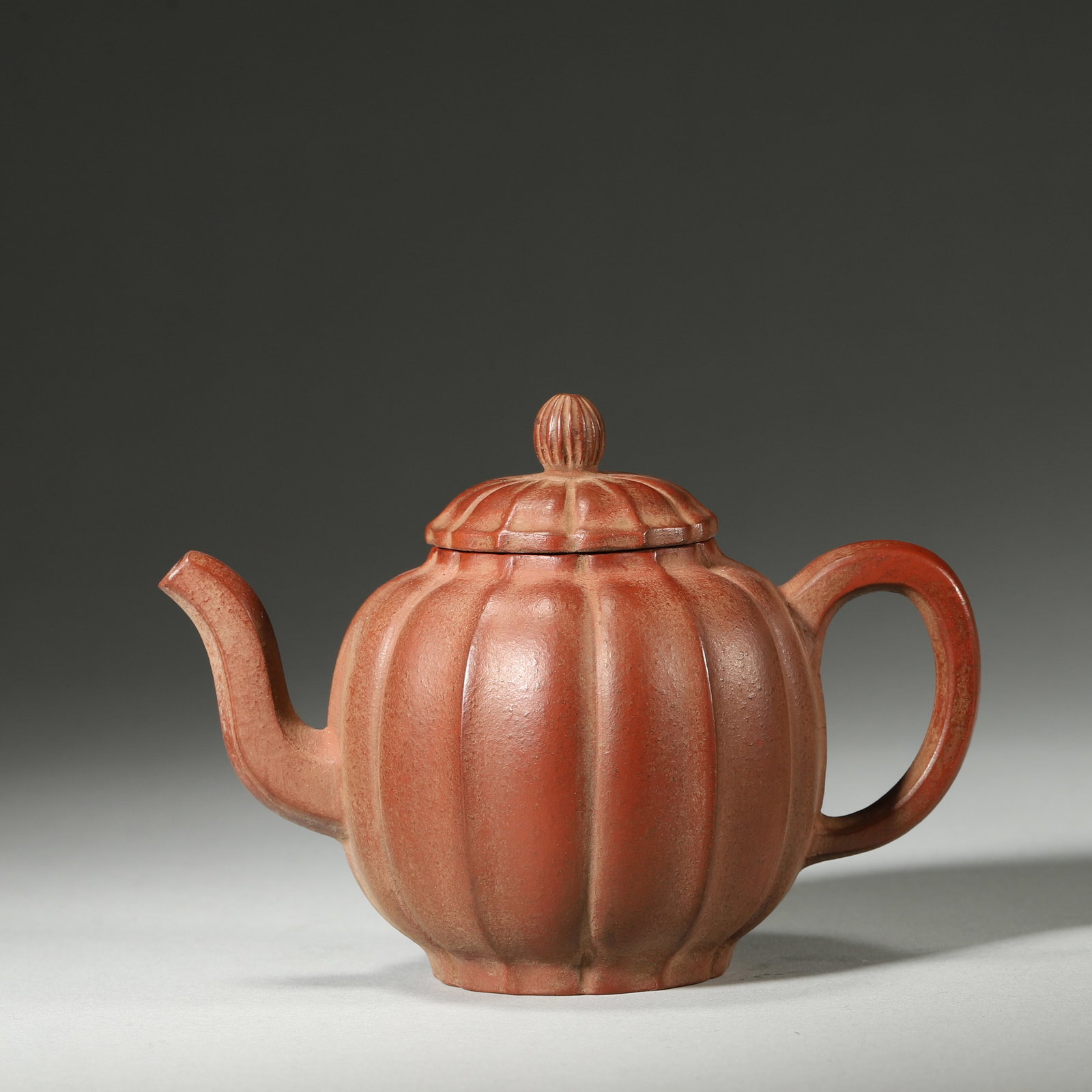 A FINE MID-QING DYNASTY (18TH–19TH CENTURY) ZHUNI CLAY MELON-FORM TEAPOT: 4.53" x 2.76" x 3.15" inches (11.5 cm x 7.0 cm x 8.0 cm)This elegant Mid-Qing teapot is crafted from fine Zhuni clay, with a rich patina and a well-proportioned melon form. Its delicate finial and