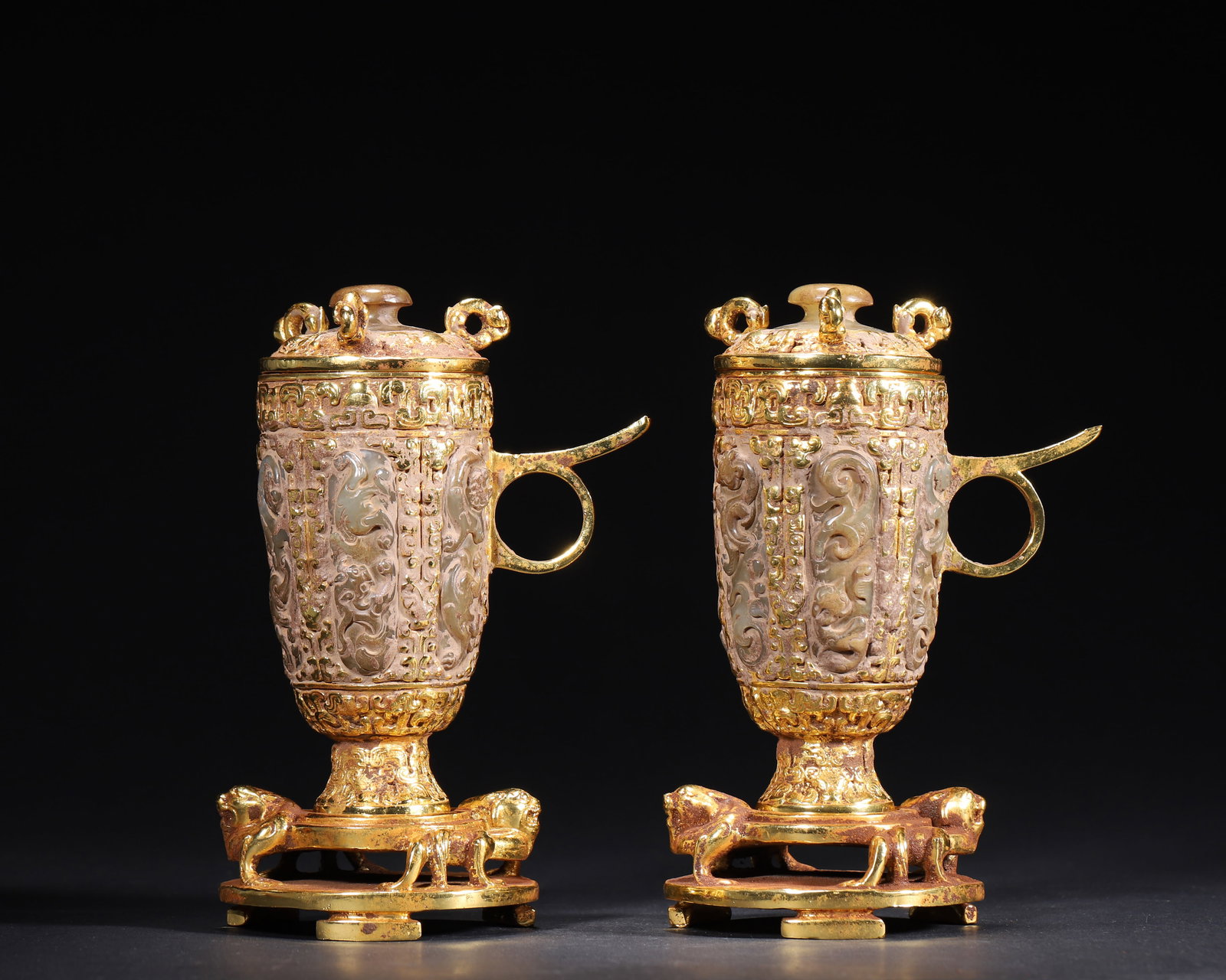 HAN DYNASTY GILT-BRONZE AND JADE INLAID COVERED CUPS WITH DIVINE BEAST MOTIFS (A PAIR): 3.15" x 6.69" inches (8.0 cm x 17.0 cm) | Weight: 4.54 lbs (2058.0 g)A magnificent pair of Han Dynasty aristocratic cups, featuring a gilt-bronze frame inlaid with jade, adorned with intricate divine