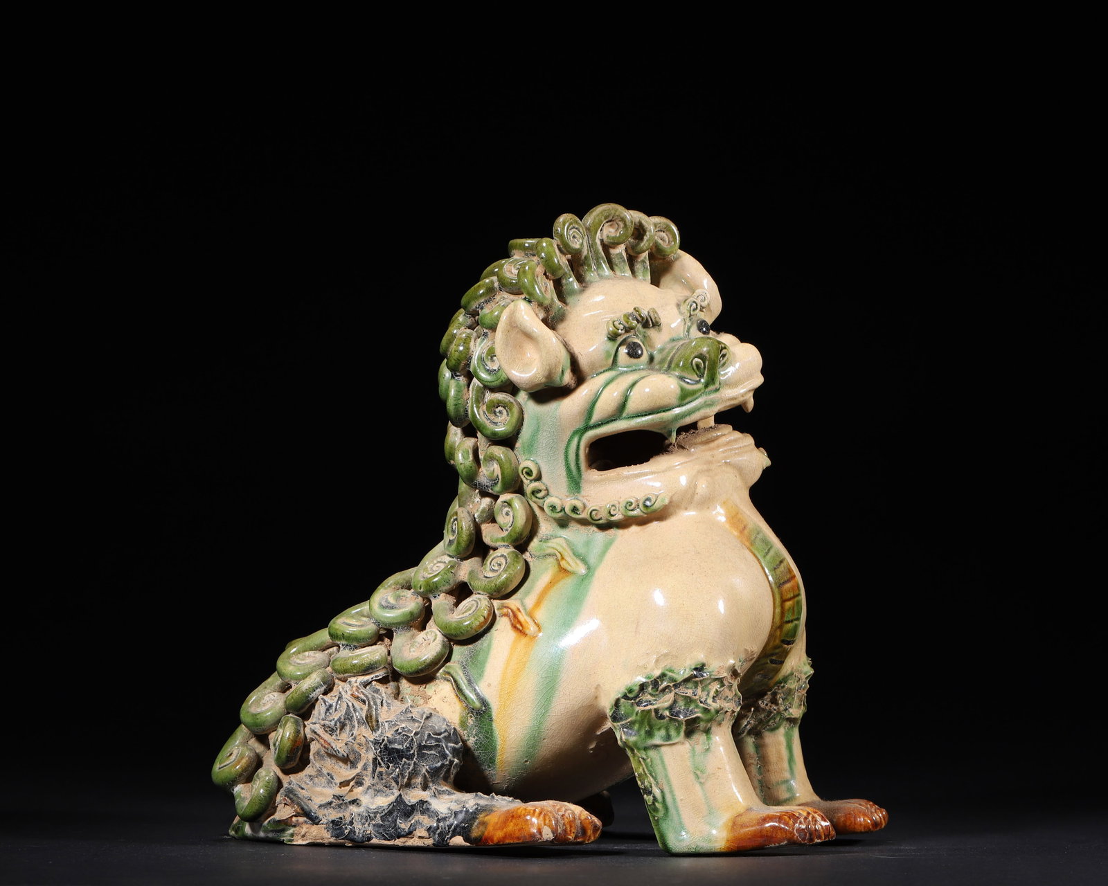 A TANG DYNASTY (618-907 AD) SANCAI-GLAZED POTTERY FIGURE OF A SEATED LION: 7.87" x 5.91" x 8.27" inches (20.0 cm x 15.0 cm x 21.0 cm) | Weight: 3.66 lbs (1659.0 g)This impressive Tang Dynasty figure depicts a seated lion with a spiraled mane, glazed in the characteristic san