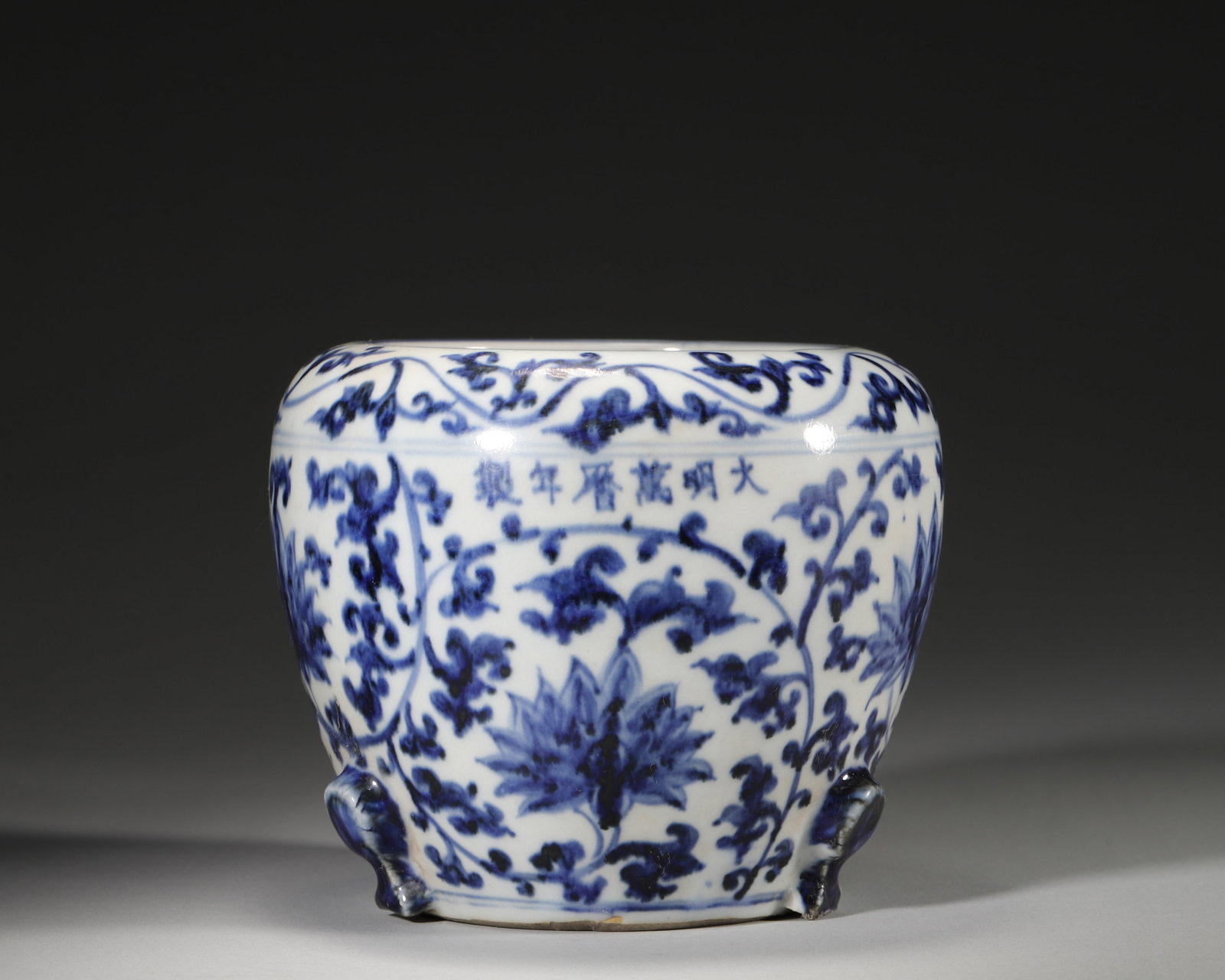 MING DYNASTY WANLI PERIOD BLUE AND WHITE TRIPOD JAR WITH INTERLOCKING LOTUS SCROLLS: 5.91" x 5.12" inches (15.0 cm x 13.0 cm)An official kiln jar from the Wanli period of the Ming Dynasty, featuring vibrant cobalt-blue interlocking lotus scrolls and a robust tripod form. It exemplifie
