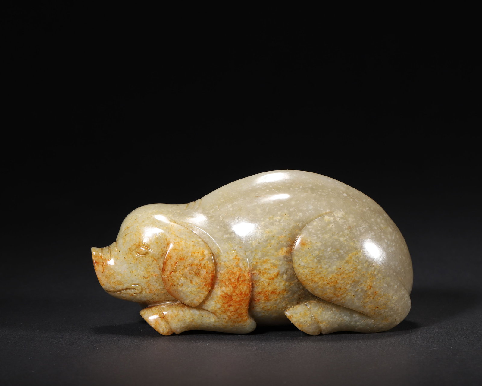 HETIAN JADE RECLINING PIG PENDANT, MING DYNASTY: 4.33" x 1.97" x 2.36" inches (11.0 cm x 5.0 cm x 6.0 cm) | Weight: 1.14 lbs (519.0 g)A fine scholar's object from the Ming Dynasty, carved from Hetian jade as a reclining pig. Its plump form, simple l