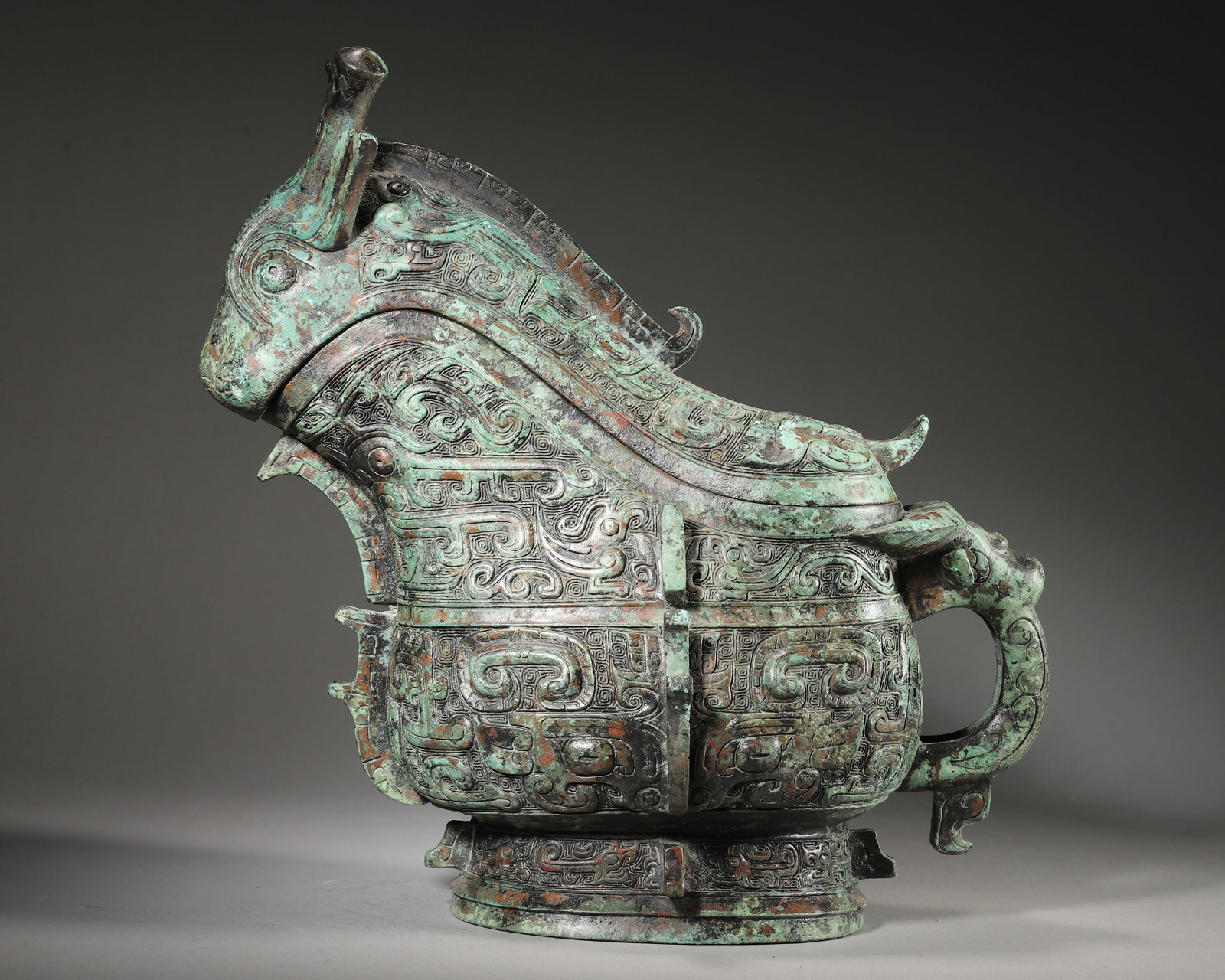 AN IMPORTANT ARCHAIC BRONZE ANIMAL-FORM RITUAL VESSEL (GONG), EARLY WESTERN ZHOU DYNASTY: L:30cm (11.81in) W:16cm (6.30in) H:29cm (11.42in) WT:4036g (8.90lb)A fine archaic bronze animal-form ritual vessel (gong), Early Western Zhou dynasty, with a fierce beast head, dragon handle, intricat