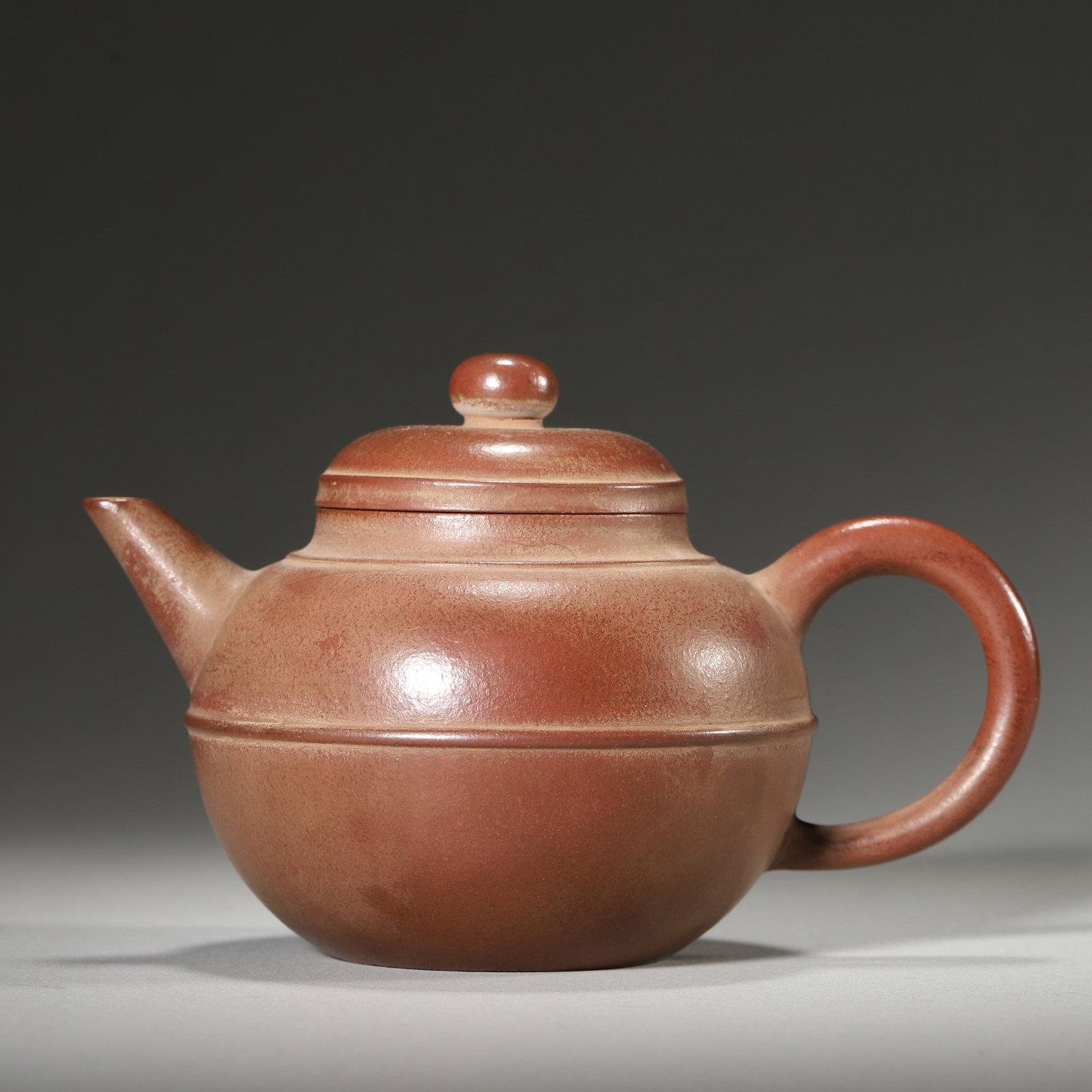 AN EARLY QING ZISHA TEAPOT, MARK OF HUI MENGCHEN: 5.12" x 3.54" x 3.54" inches (13.0 cm x 9.0 cm x 9.0 cm)Crafted from fine vermilion clay, this teapot features a rounded body with a distinct waist line, balanced spout and handle, and the base bears