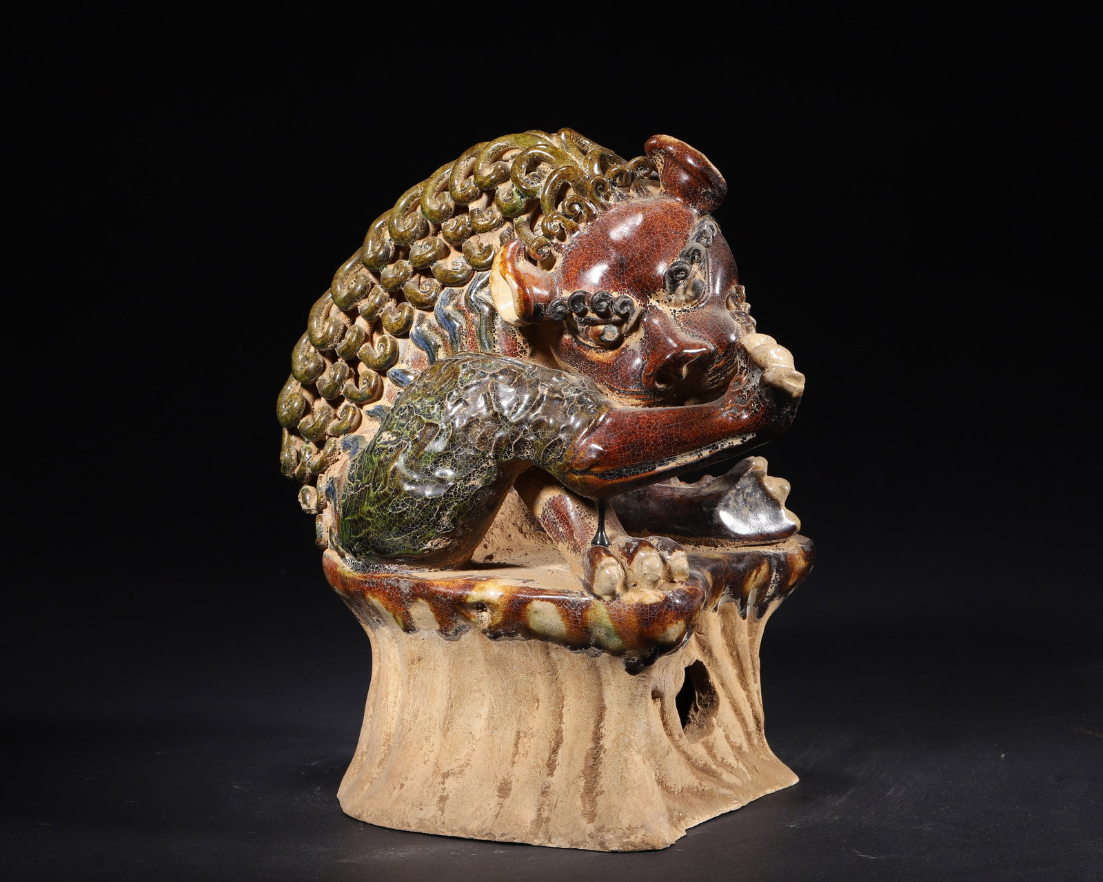 A TANG DYNASTY (618-907 AD) SANCAI-GLAZED POTTERY FIGURE OF A RECUMBENT LION: 7.87" x 5.51" x 9.06" inches (20.0 cm x 14.0 cm x 23.0 cm) | Weight: N/A (N/A)This impressive Tang Dynasty figure depicts a recumbent lion licking its paw, glazed in the characteristic sancai palette