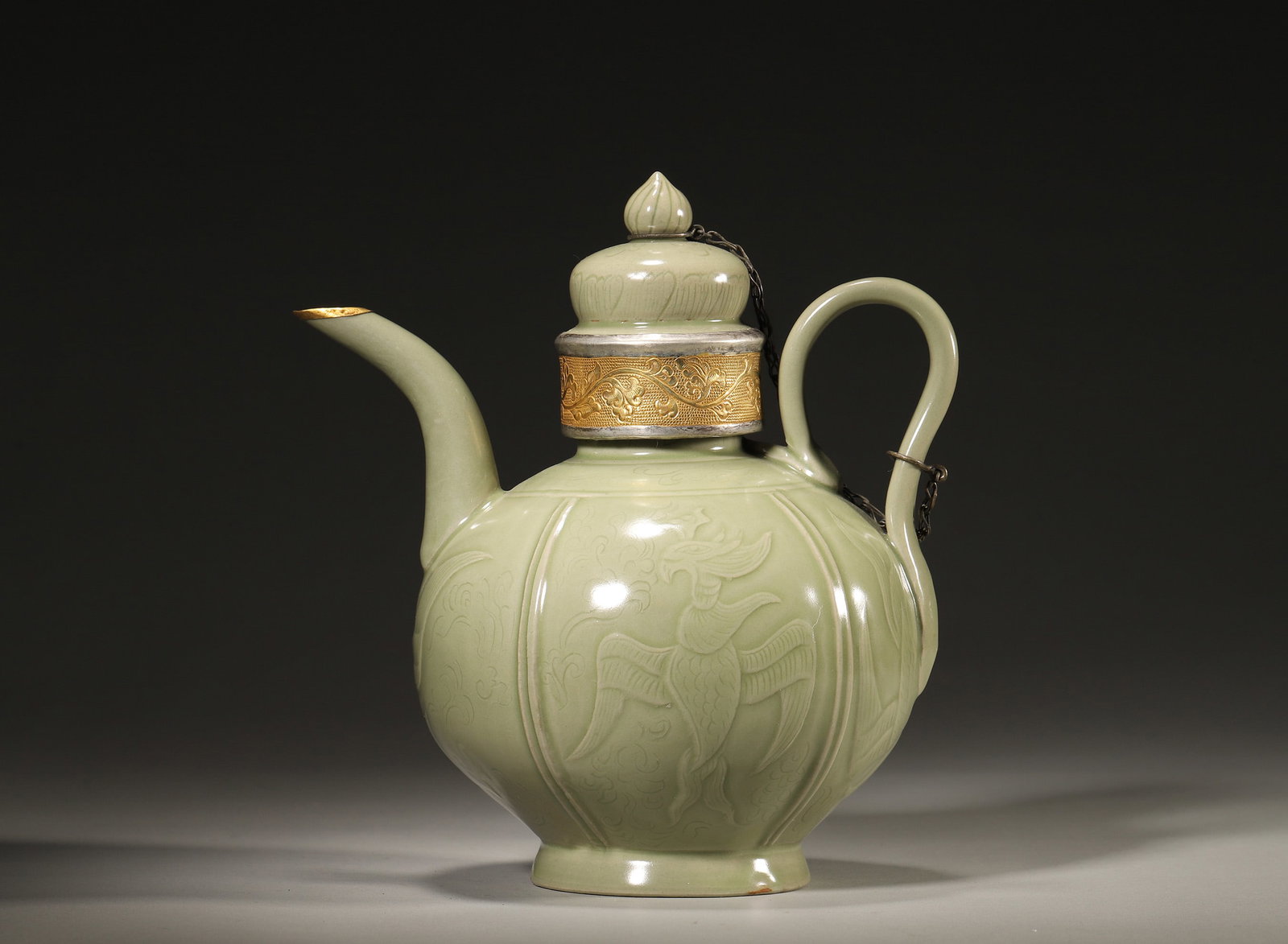 A NORTHERN SONG DYNASTY YAOZHOU CELADON EWER WITH INCISED PHOENIX DESIGN AND GILT-SILVER MOUNTED RIM: 7.48" x 5.51" x 8.27" inches (19.0 cm x 14.0 cm x 21.0 cm)This ewer features a rich olive-green glaze, vividly incised phoenix motifs, and an elegant gilt-silver mount. A masterpiece of Northern Song