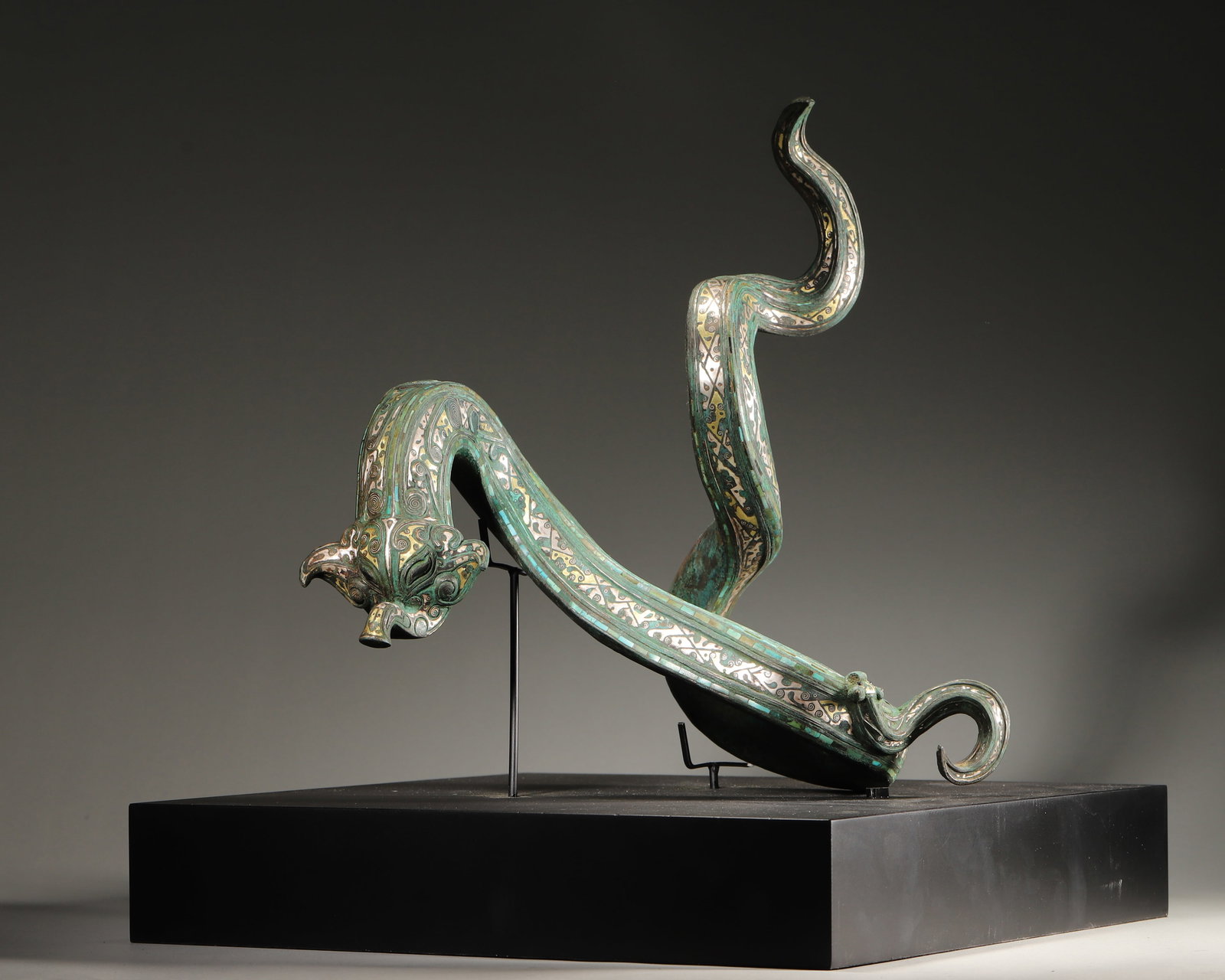 AN IMPORTANT ARCHAIC BRONZE DRAGON-FORM BELT HOOK WITH GOLD AND SILVER INLAY AND TURQUOISE INLAY,: L:28cm (11.02 in) W:25cm (9.84 in) H:32cm WT:3130gA fine archaic bronze dragon-form belt hook, Late Warring States period, with gold and silver inlay, turquoise inlay, of exceptional craftsmanship and