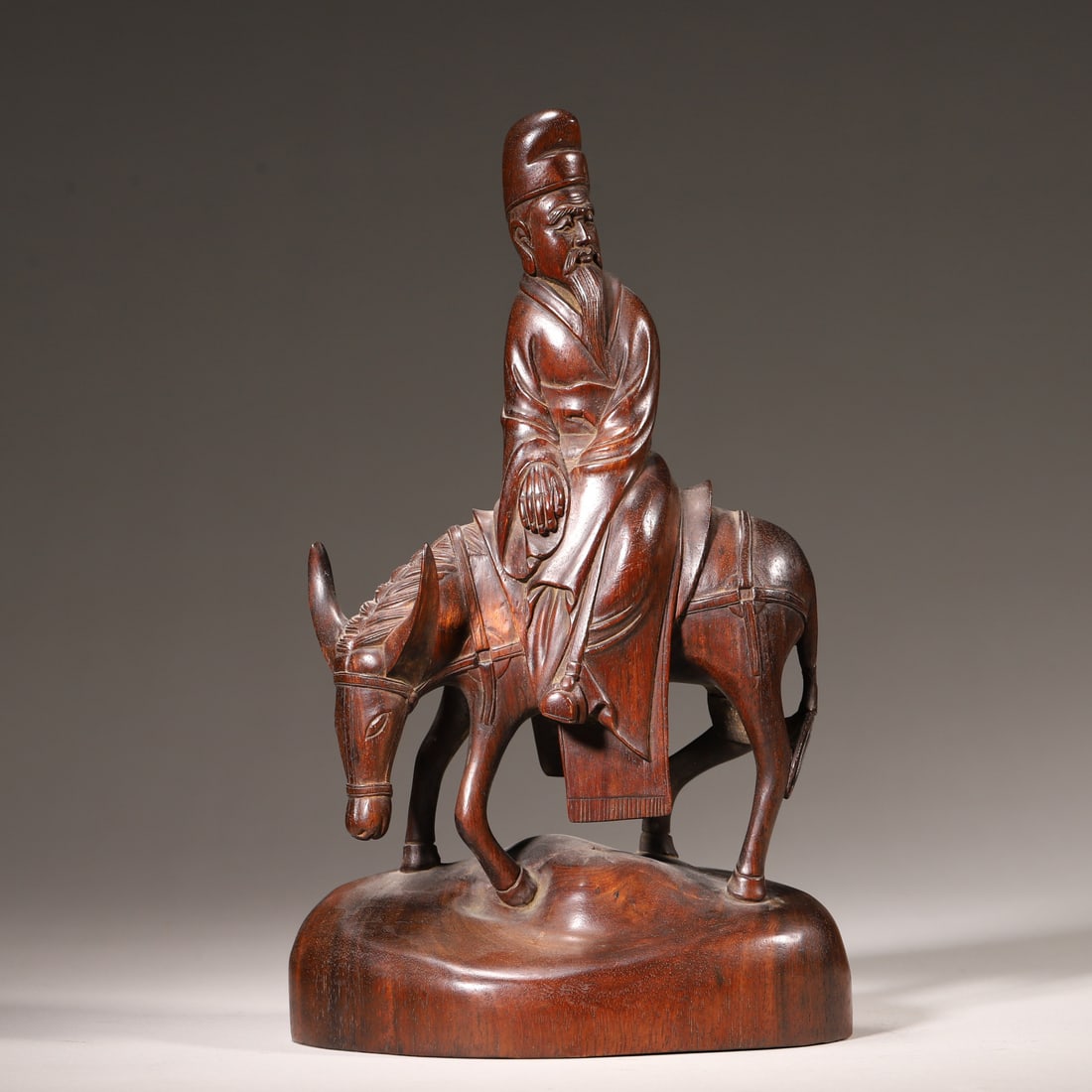 A Hardwood Carved "Scholar on Donkey" Group, Qing Dynasty: L 13.0cm (5.12 in); W 9.0cm (3.54 in); H 22.0cm (8.66 in); Wt 464.0g (1.02 lb)This group is carved from a single hardwood piece, depicting a robed scholar riding a donkey. With concise carving and ric