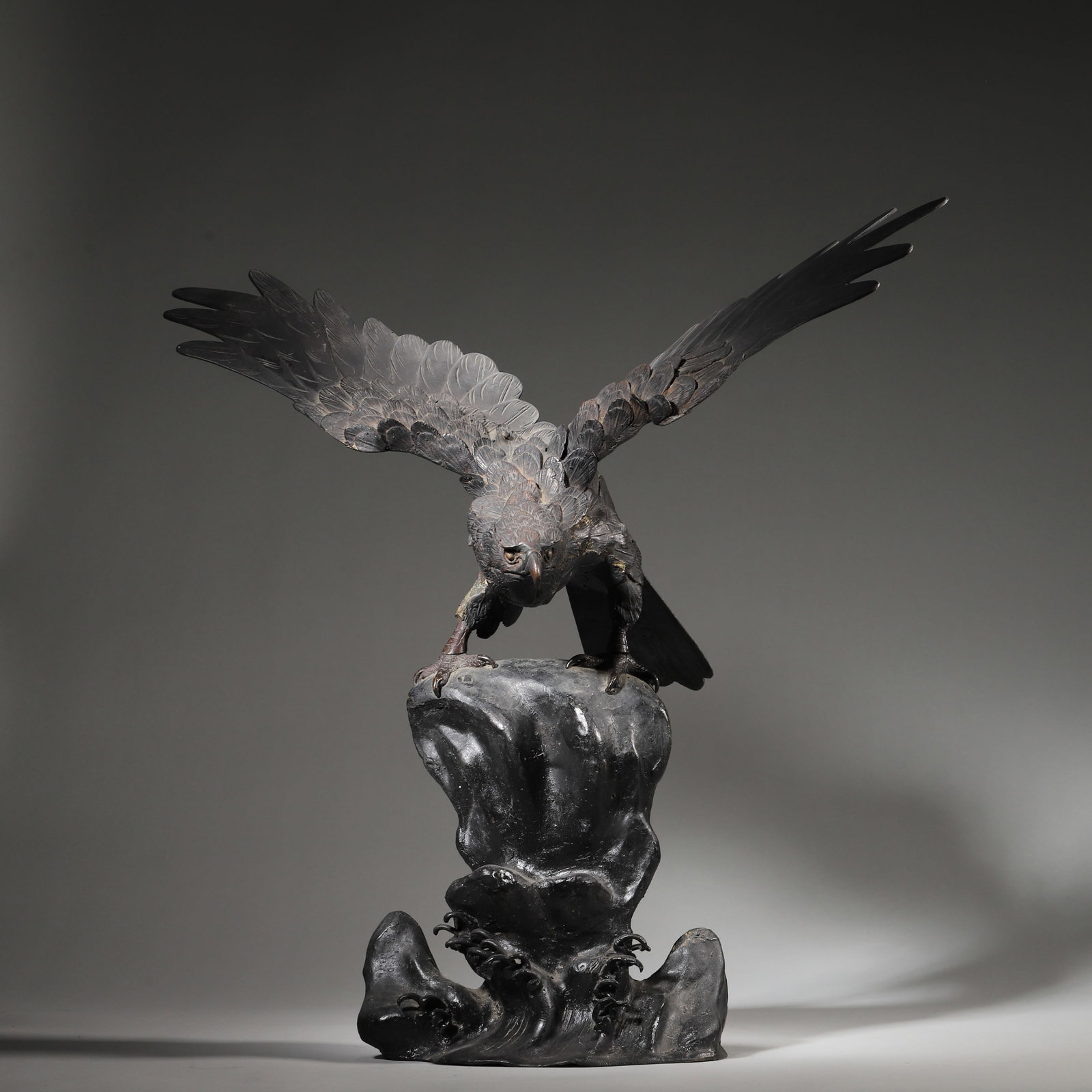 A Bronze Eagle Sculpture, Qing Dynasty: L 47.0cm (18.5 in); W 25.0cm (9.84 in); H 46.0cm (18.11 in); Wt 4638.0g (10.23 lb)This bronze sculpture depicts an eagle with outstretched wings perched on a rocky base, showcasing detailed feather te