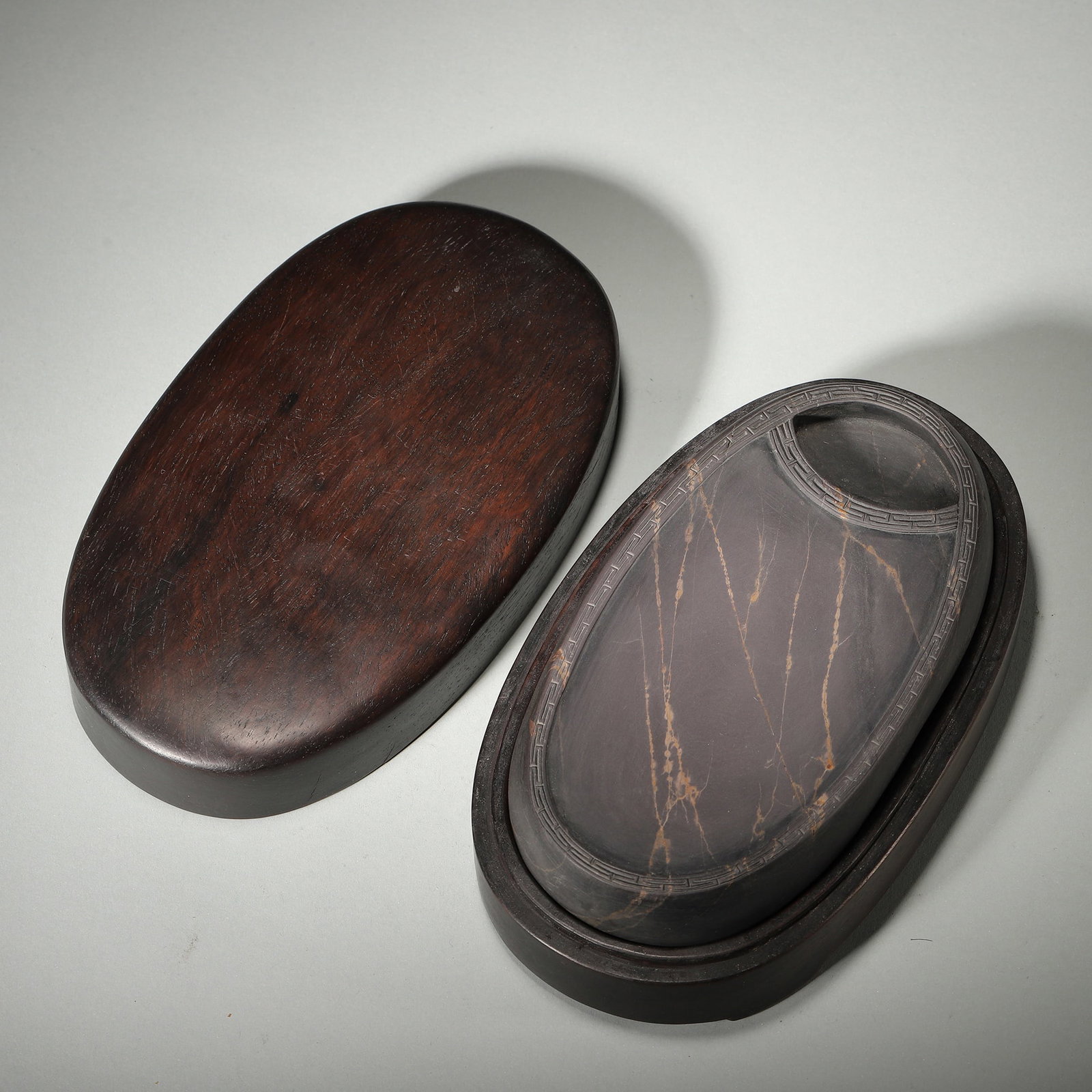 A Duanxi Laokeng Inkstone with Huiwen Border, Qing Dynasty: L 16.0cm (6.3 in); W 8.0cm (3.15 in); Wt 924.0g (2.04 lb)This inkstone is carved from fine Duanxi Laokeng stone, featuring a huiwen border and natural ice veins. With a matching hardwood box, it is a 