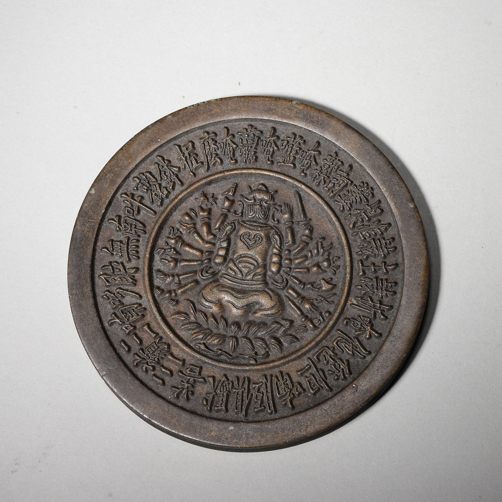A Bronze Mirror with Cundi Bodhisattva and Sanskrit Inscriptions, Ming Dynasty: D 10.5cm (4.13 in); Wt 495.0g (1.09 lb)This Ming Dynasty bronze mirror features a relief of Cundi Bodhisattva with Chinese and Sanskrit mantras. With fine craftsmanship and rich patina, it is a devoti