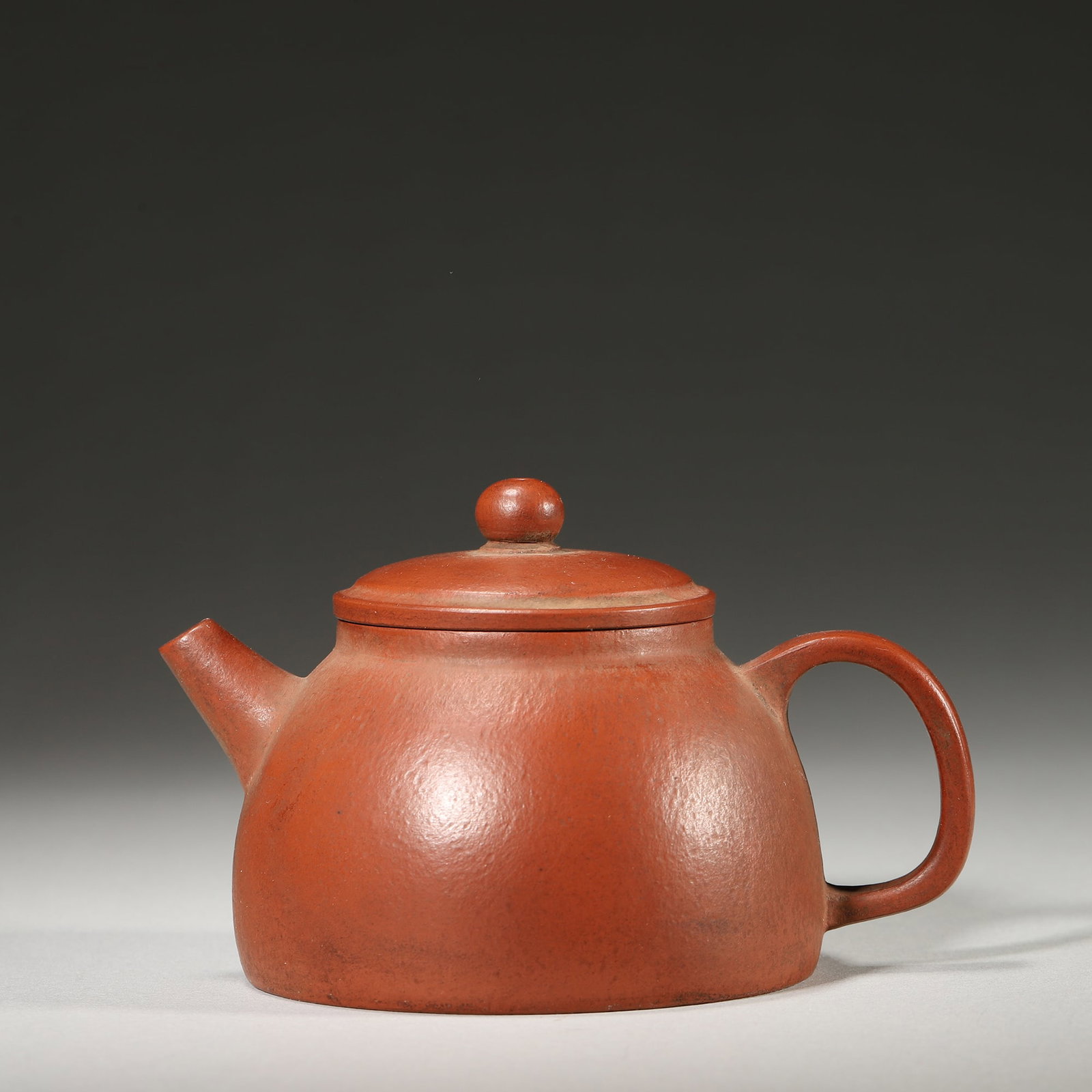 A Miniature Zhuni Zisha Teapot with Poem Mark, Qing Dynasty: L 11.0cm (4.33 in); W 8.0cm (3.15 in); H 7.0cm (2.76 in)This miniature teapot is crafted from fine Zhuni clay, with a simple and elegant form. It bears a poem mark at the base and has a natural patina