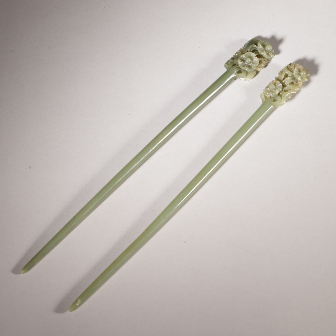 A Pair of Hetian Celadon Jade Hairpins with Openwork Floral Design, Ming Dynasty: L 27.5cm (10.83 in); W 2.5cm (0.98 in); Wt 80.0g (0.18 lb)A pair of Hetian celadon jade hairpins from the Ming Dynasty, carved with openwork floral designs at the top. The jade is warm and lustrous, w