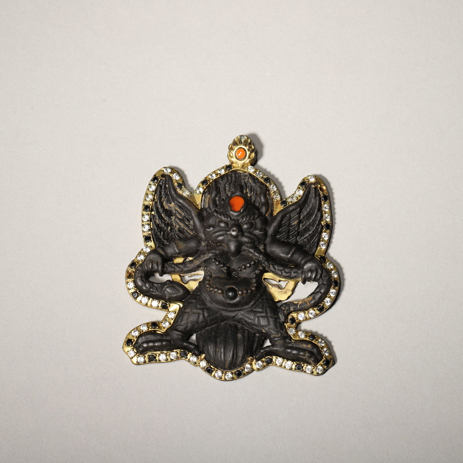 A Sky-Iron Pendant of Garuda, Qing Dynasty: L 7.0cm (2.76 in); W 5.8cm (2.28 in); Wt 56.0g (0.12 lb)A Qing Dynasty pendant of Garuda made from sky-iron, with a vajra motif on the reverse. With rich patina and strong religious symbolism, it is a